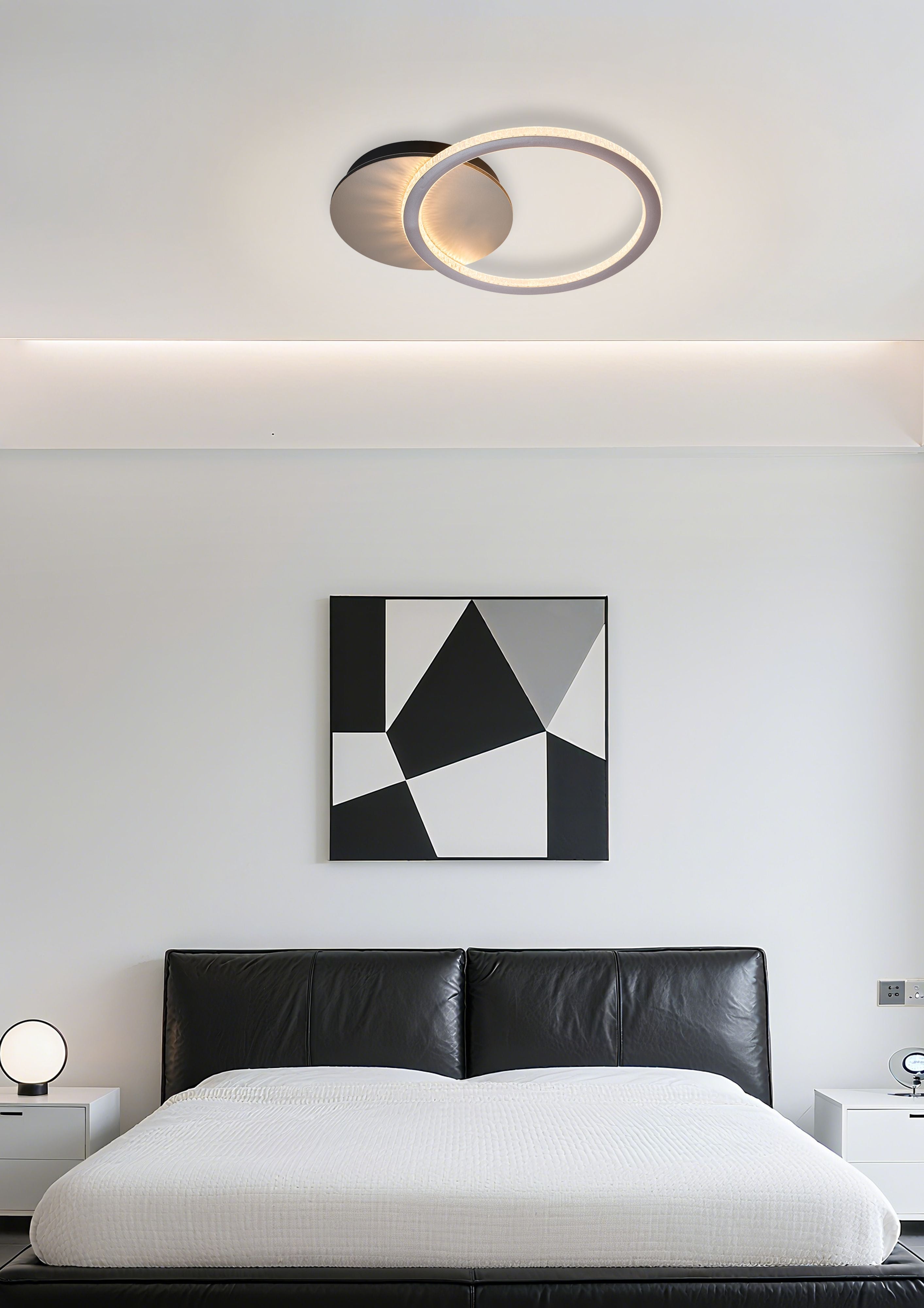 Specs single ring LED flush light in champagne metal installed above a bed with a black leather headboard and geometric wall art