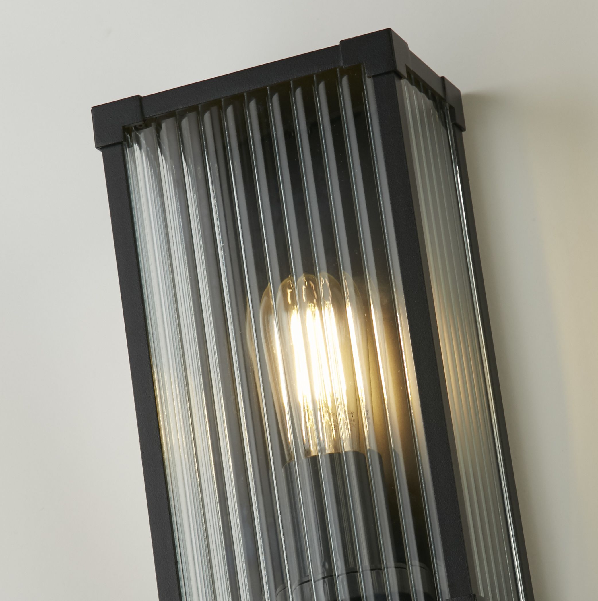 Close up of the Cincinnati wall light corner joint and ribbed glass with the bulb lit inside
