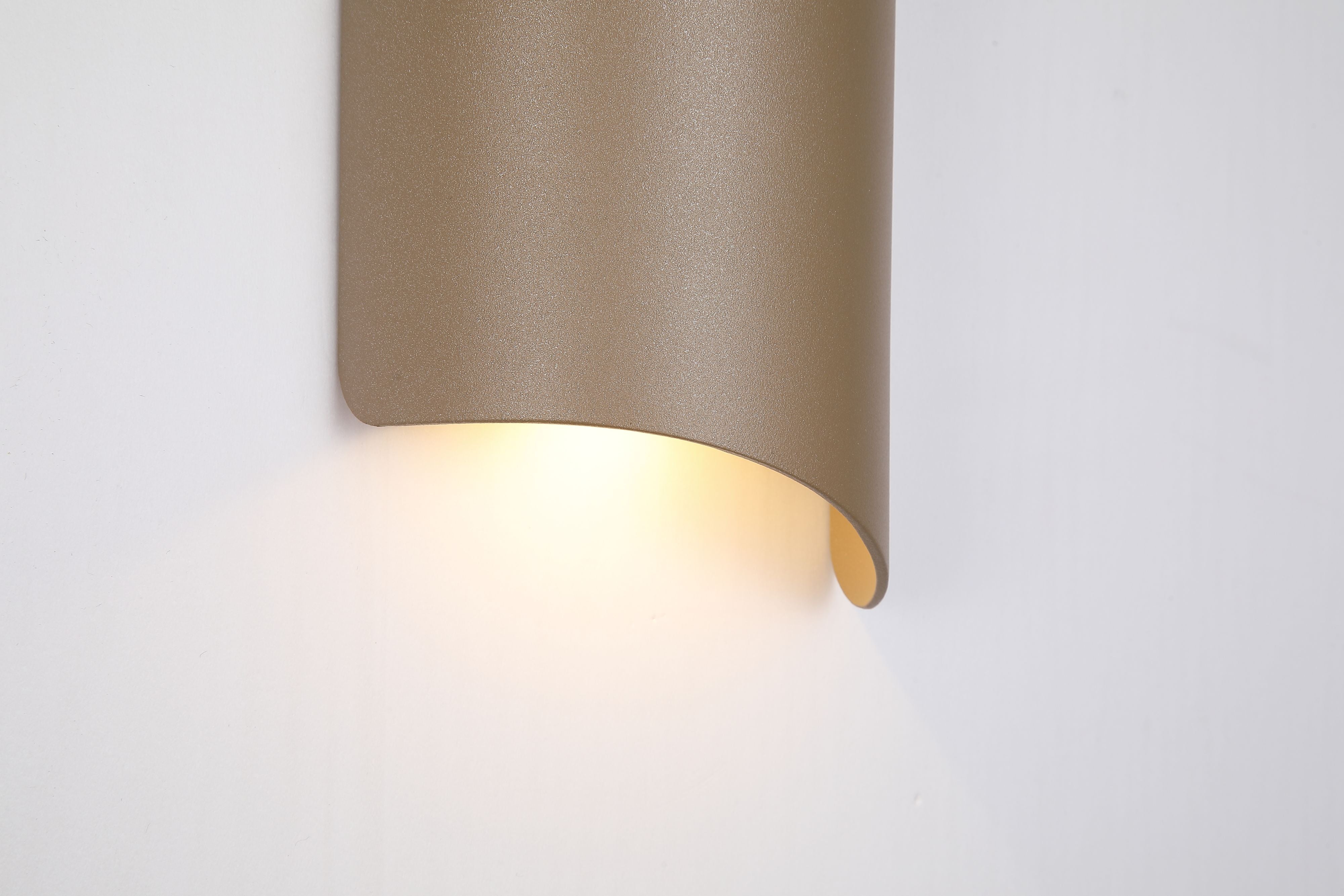 Close up of the base of the Shard outdoor wall light in gold, lit, mounted on a white exterior wall