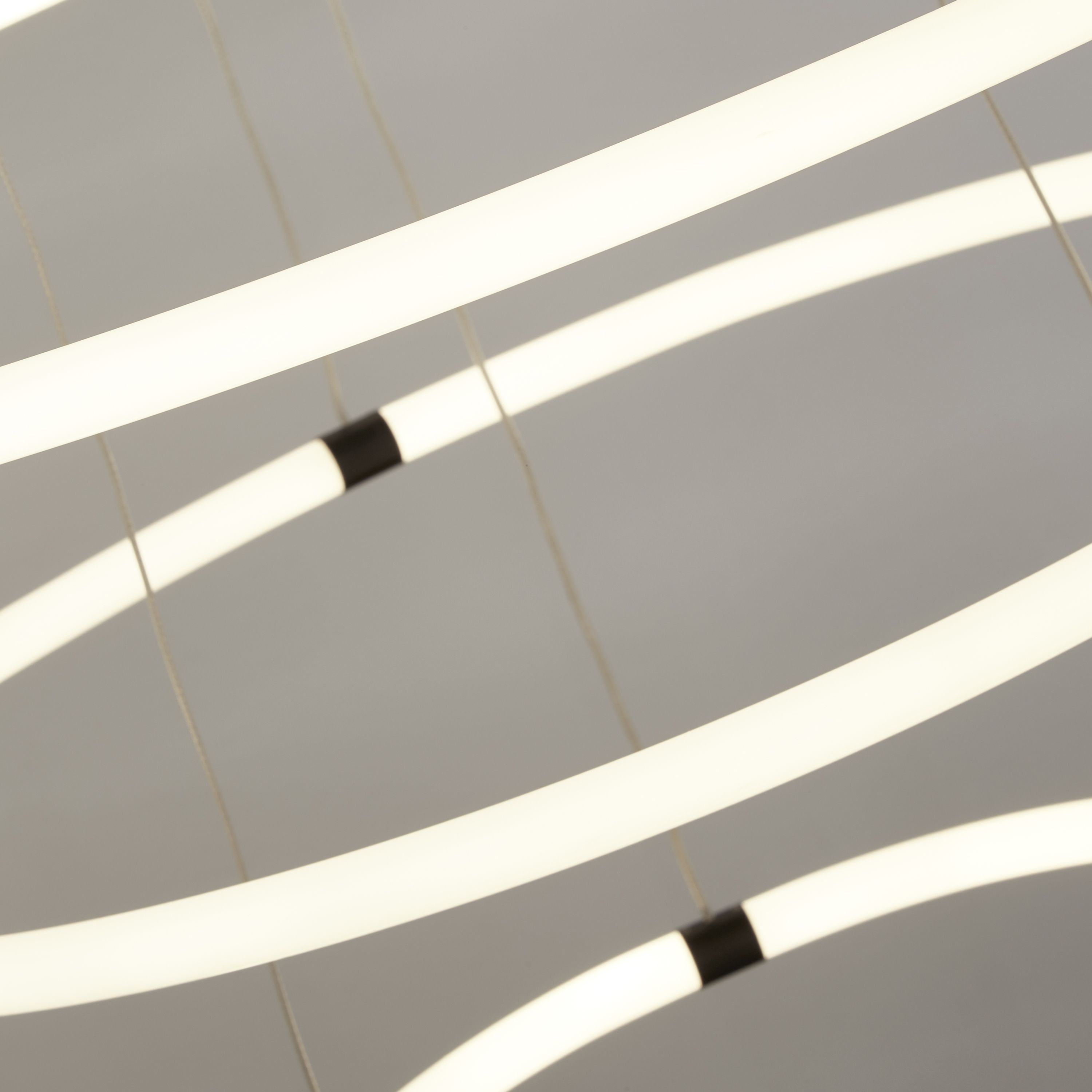 Close up of two of the Revolve 3 light ring pendant's opal rings, showing the black joins and crossing suspension cables