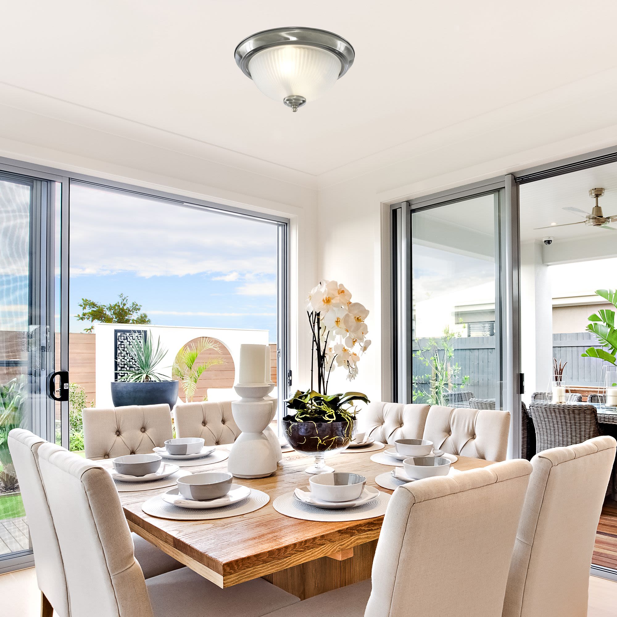 American Diner flush ceiling light in satin silver styled above a dining table set for a meal