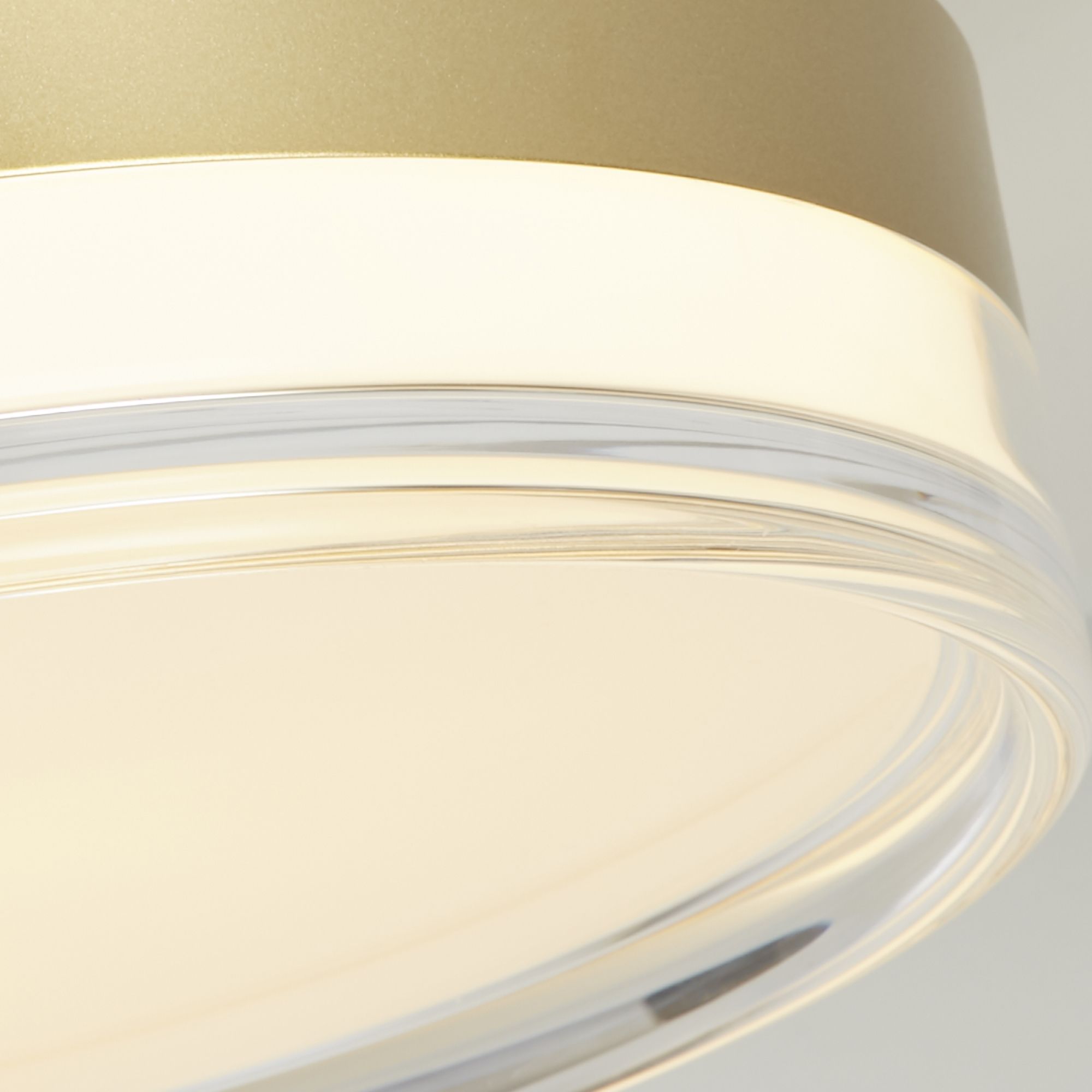 Close up of the Searchlight Cyprus LED Flush 40cm in gold, showing the brushed gold metal edge, clear acrylic trim and warm glow from the diffuser