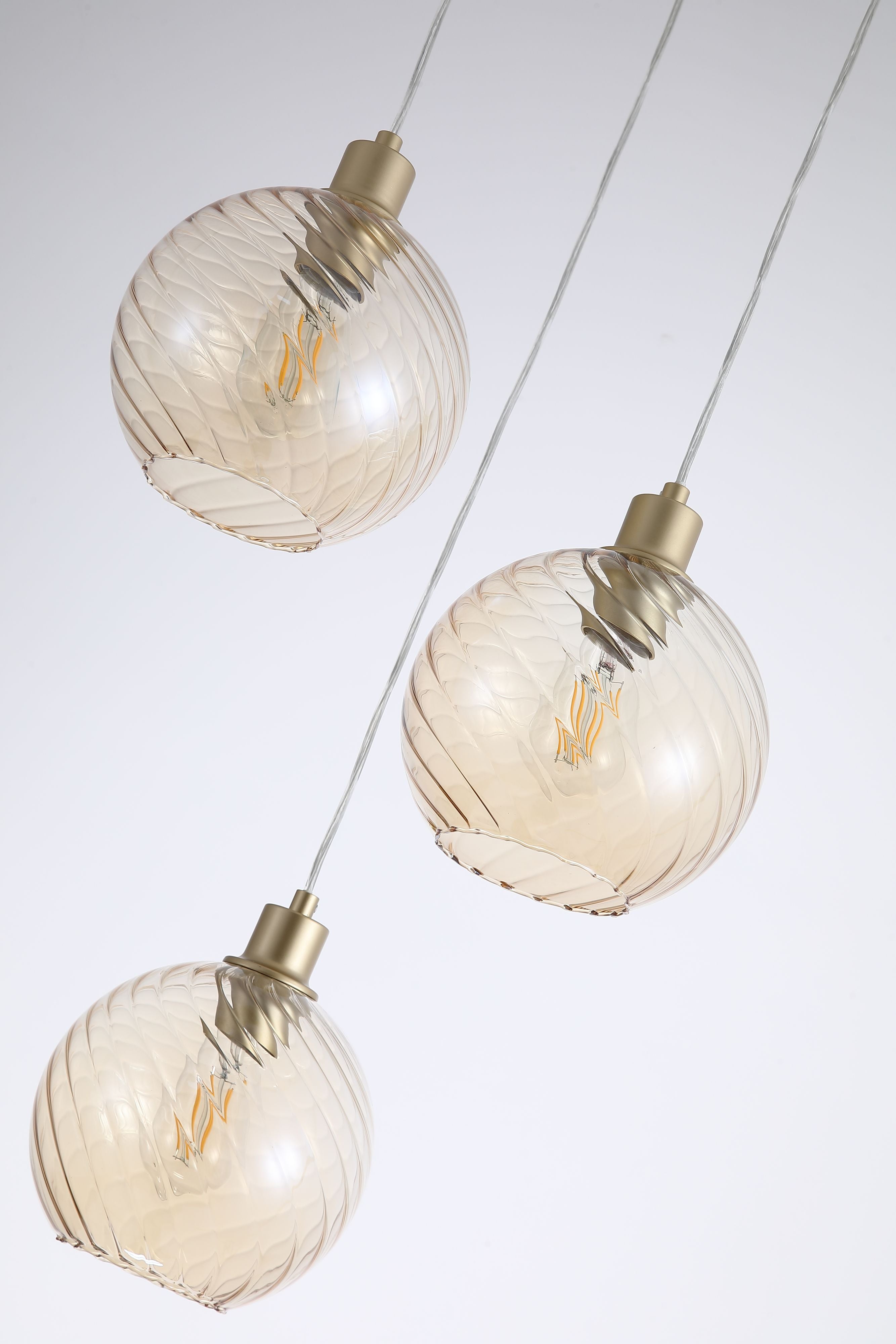 Close up of two champagne swirled glass globe shades on the Searchlight Radiance Multi Drop Pendant, showing the gold lamp holders and swirl texture