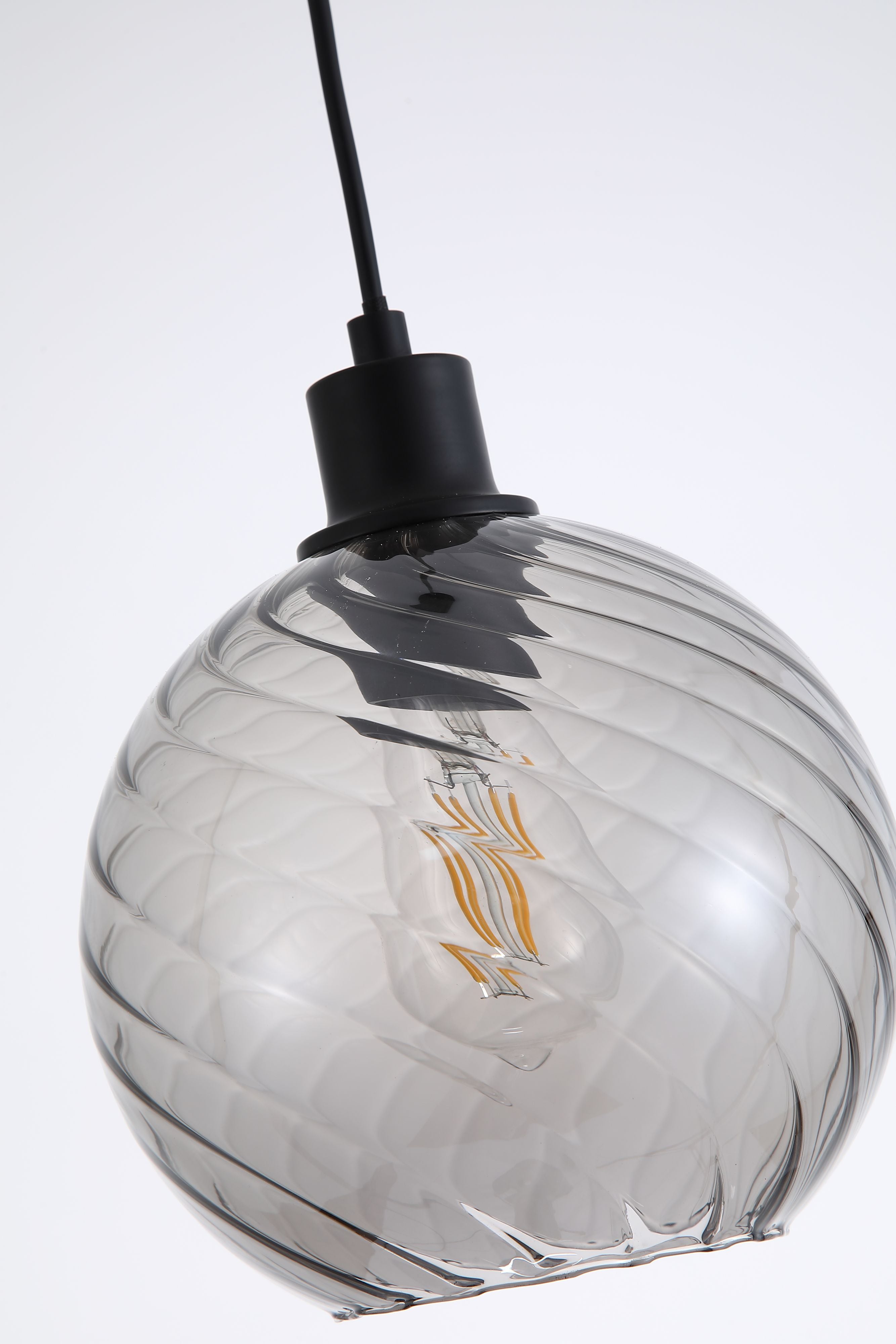 Close up of the smoked glass globe on the Radiance 1 Light Pendant, showing the swirled texture and the glowing filament style bulb inside