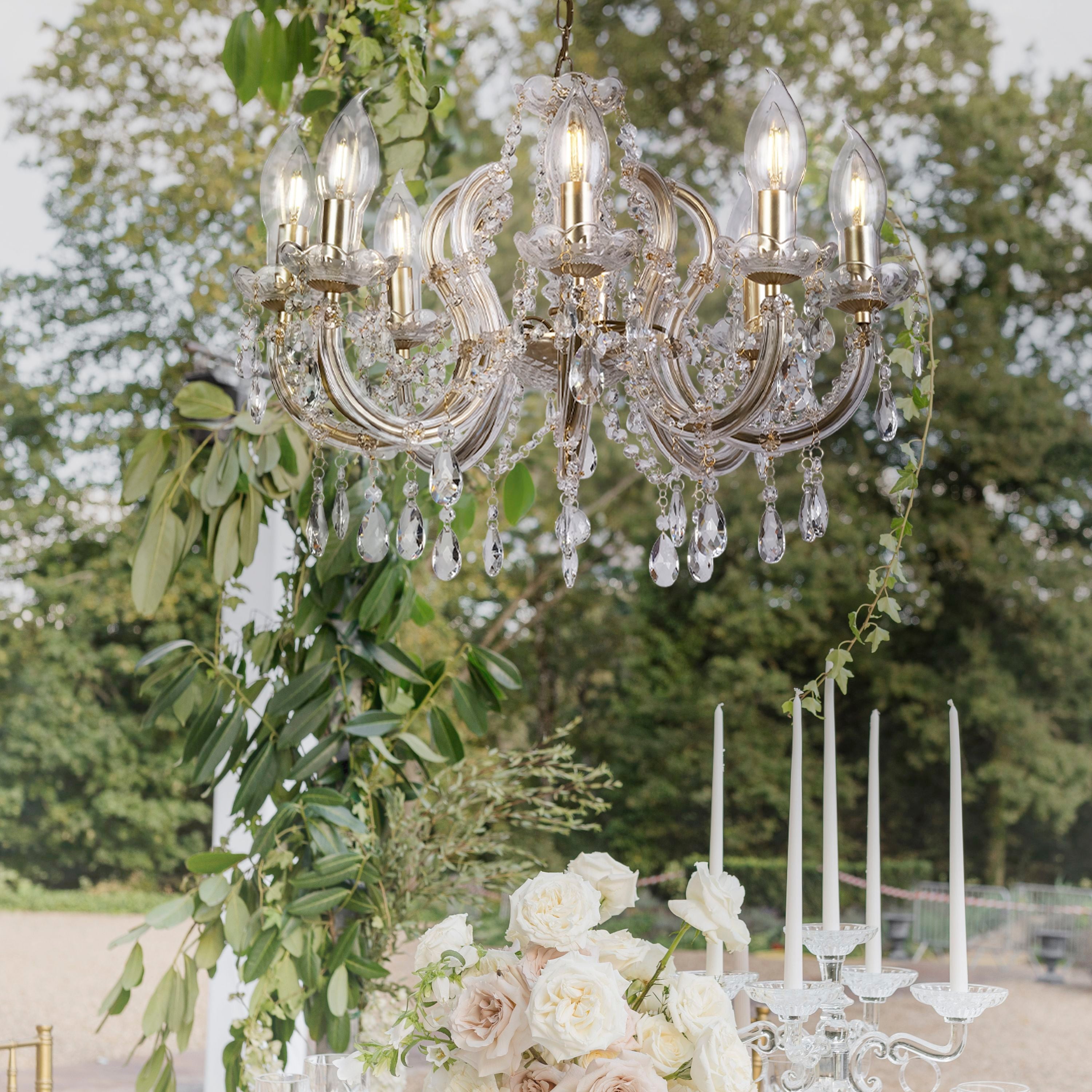 Utah gold pendant hanging outdoors above a table styled with white roses and candles at a wedding reception, lit with trees in the background