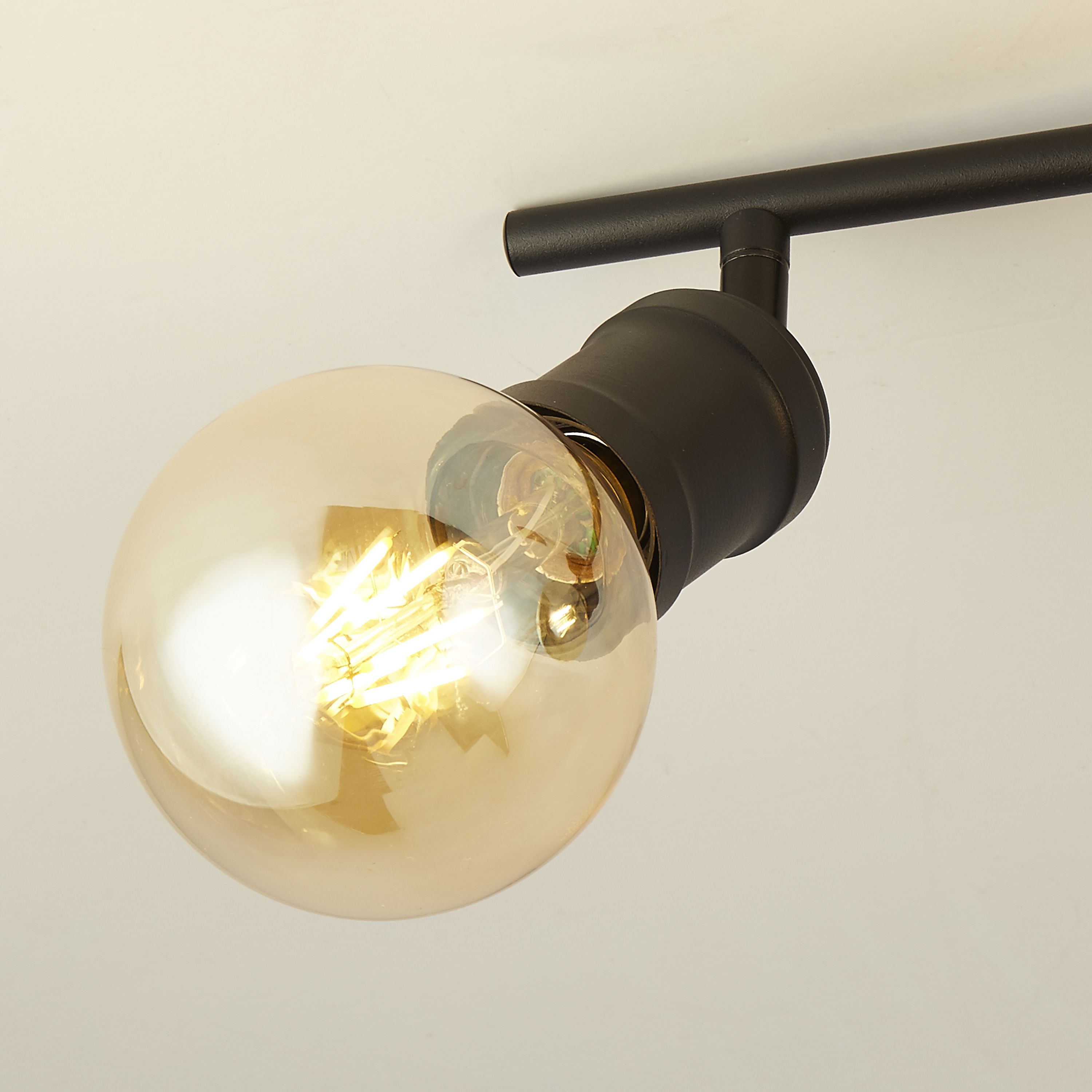 Close up of one bulb holder on the Searchlight Dance split bar spotlight, showing the adjustable black fitting and lit vintage style globe bulb