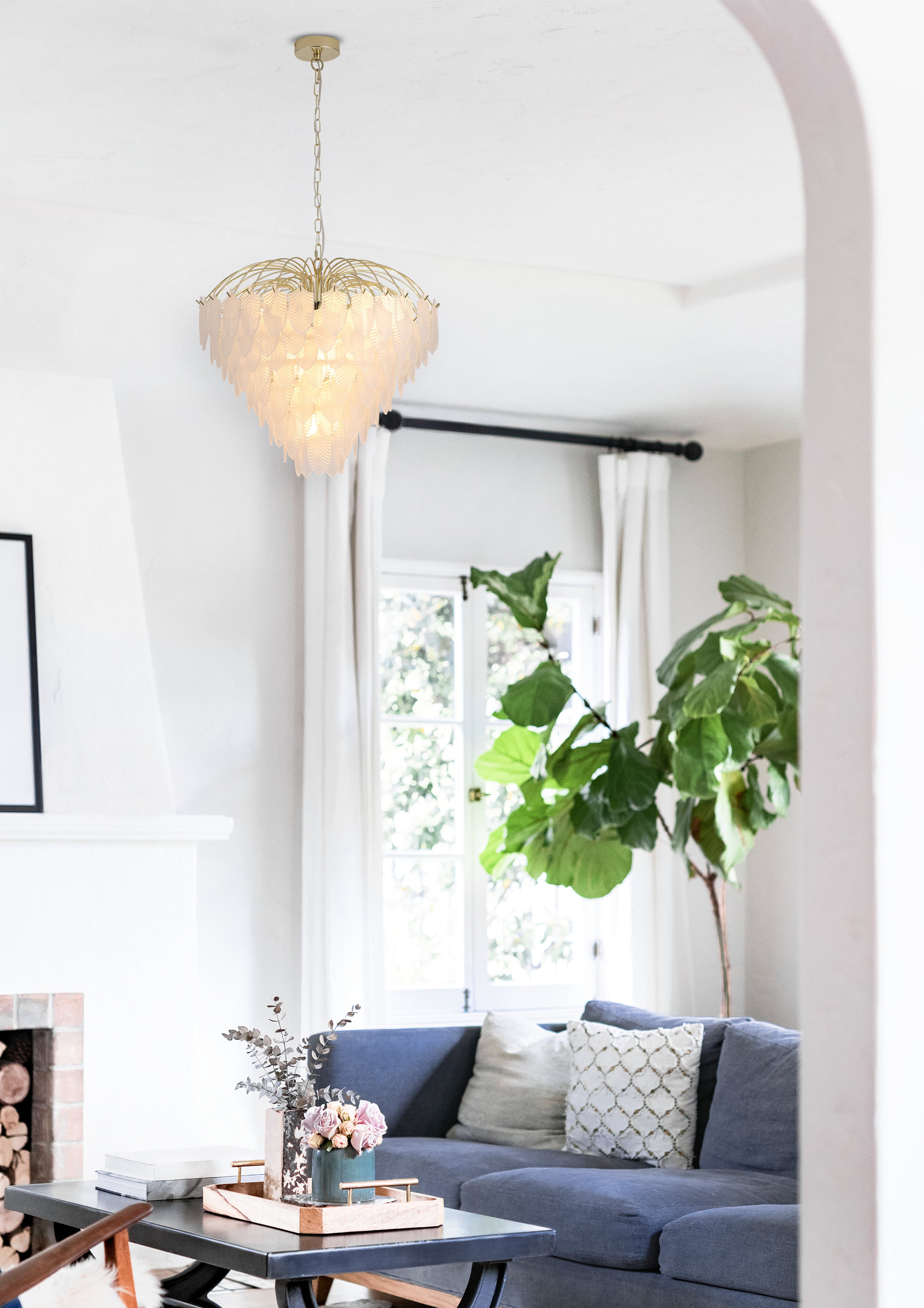 Searchlight Feather 10 light pendant in polished brass, hanging in a bright living room with a blue sofa and fireplace