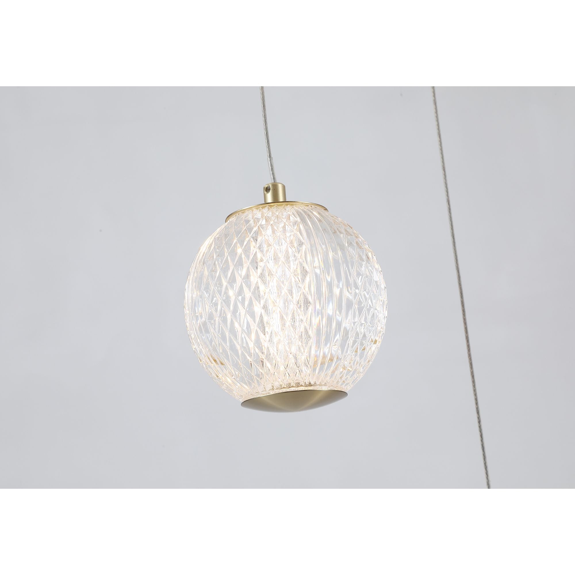 Close up of the Allure pendant's etched acrylic globe on a satin brass fitting, showing the diamond cut texture lit from within