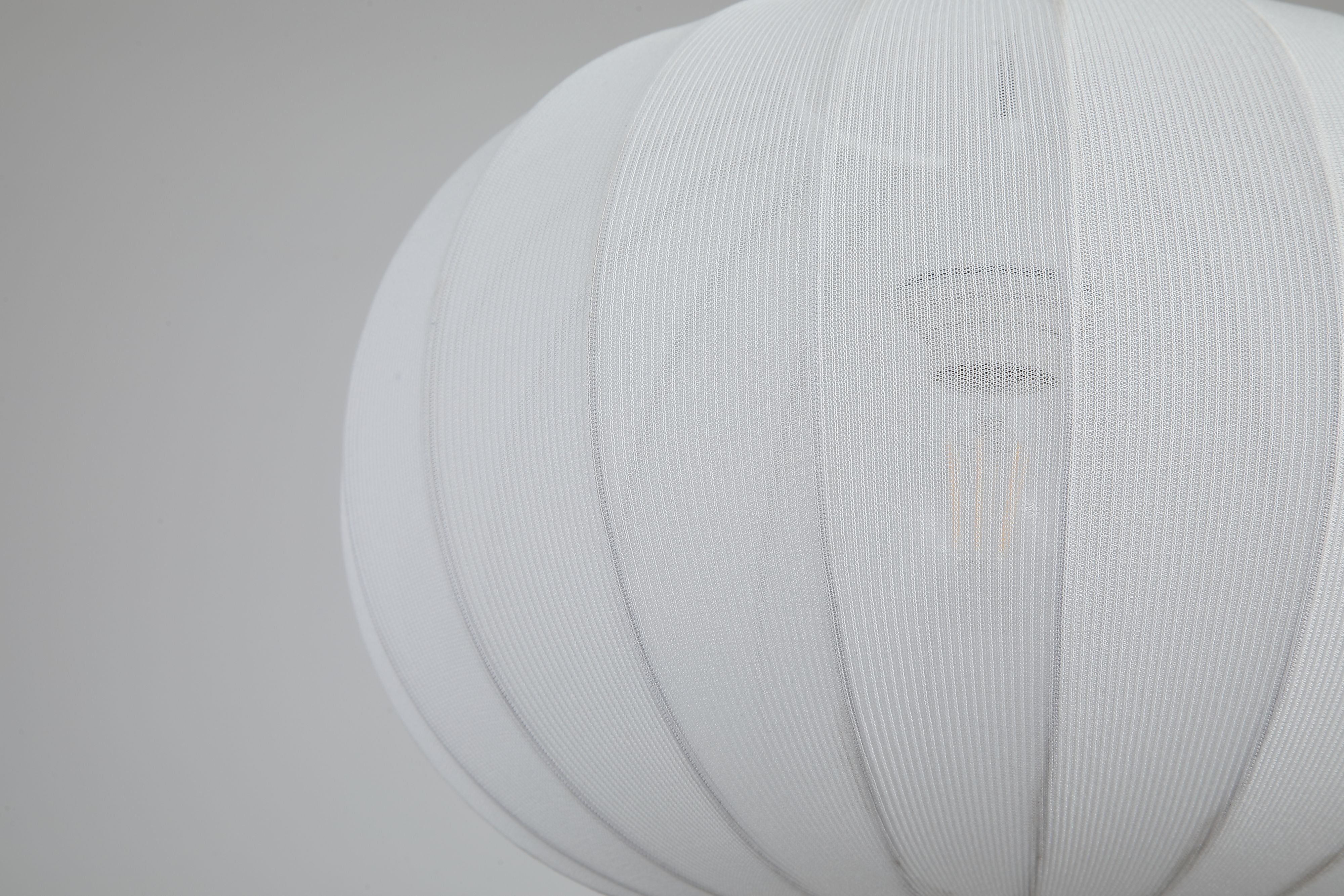 Close up of the Radiant pendant shade's fine vertical ribbing with the lit bulb visible through the fabric