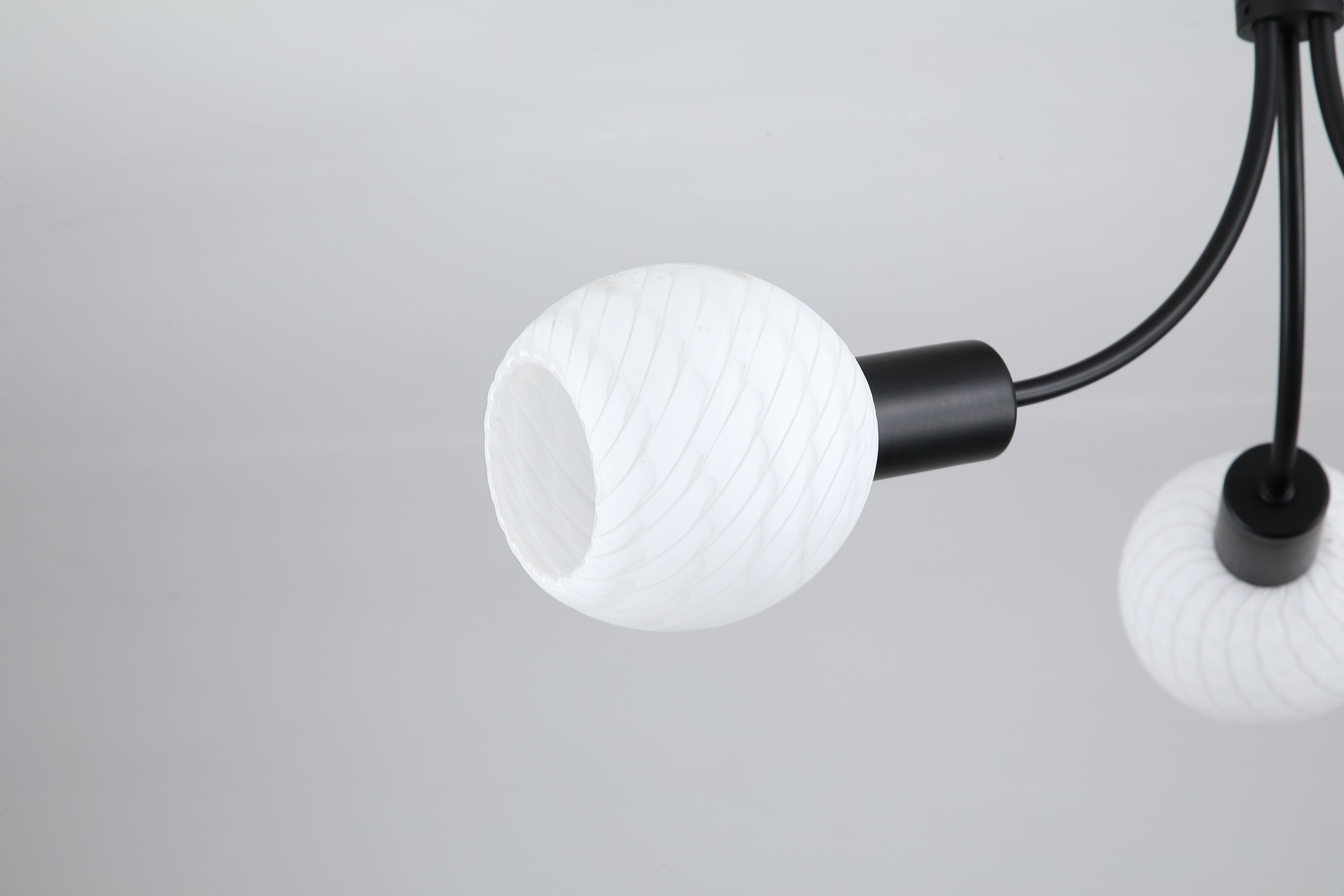Close up of a Nova ceiling lamp opal glass shade showing its fine spiral ribbed texture and black fitting