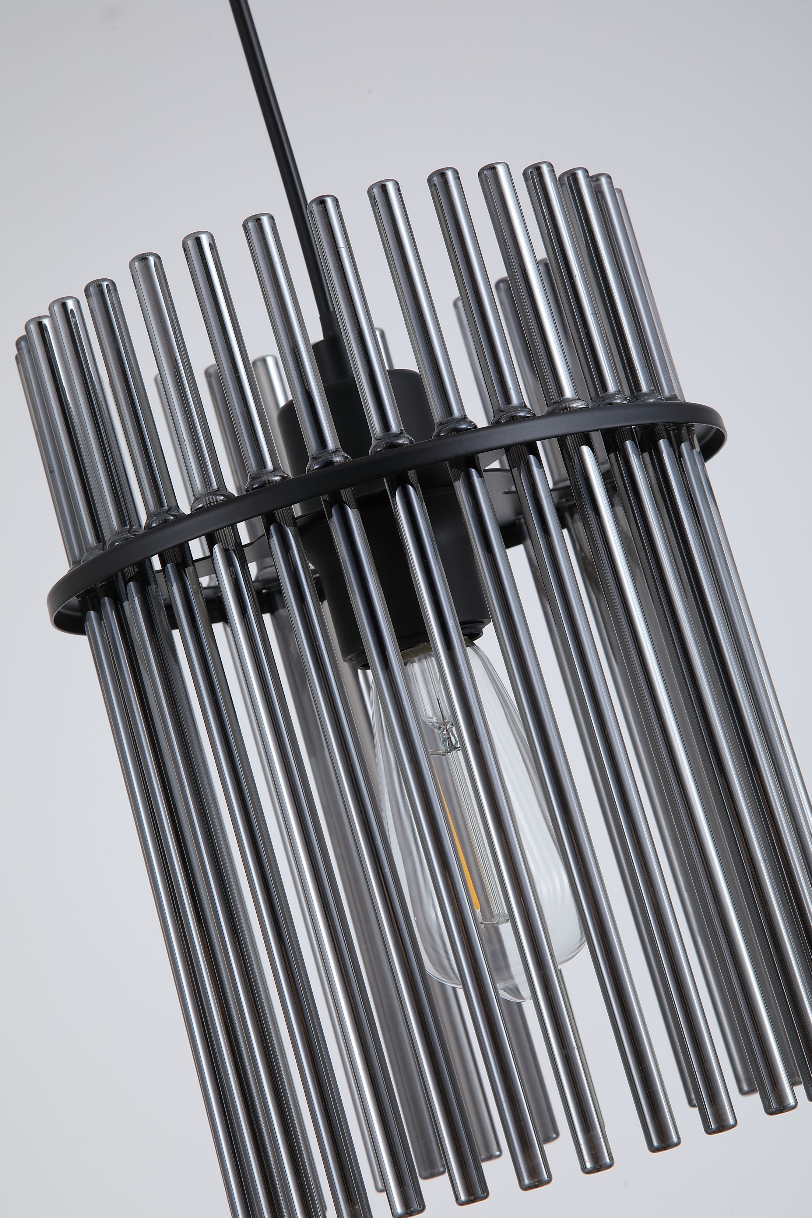 Close up of the Swizzle 20cm pendant shade, smoked glass rods around the lit E27 bulb and black mounting ring