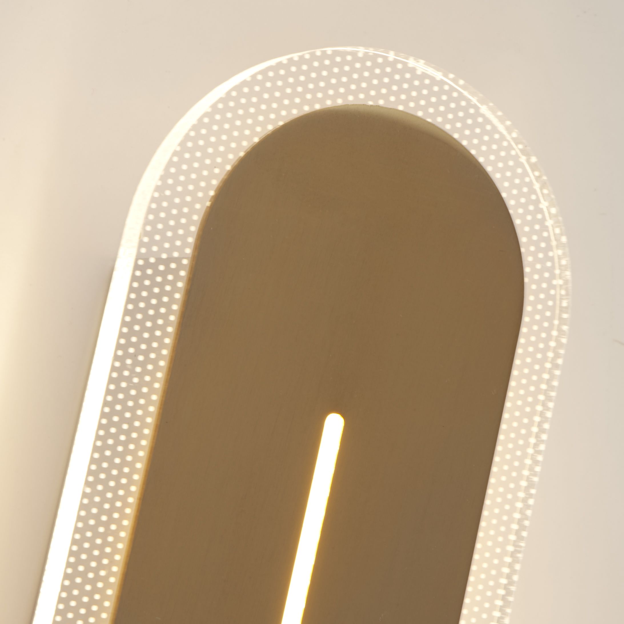 Close up of the Couper wall light's satin brass panel and vertical LED slit set within the white acrylic frame