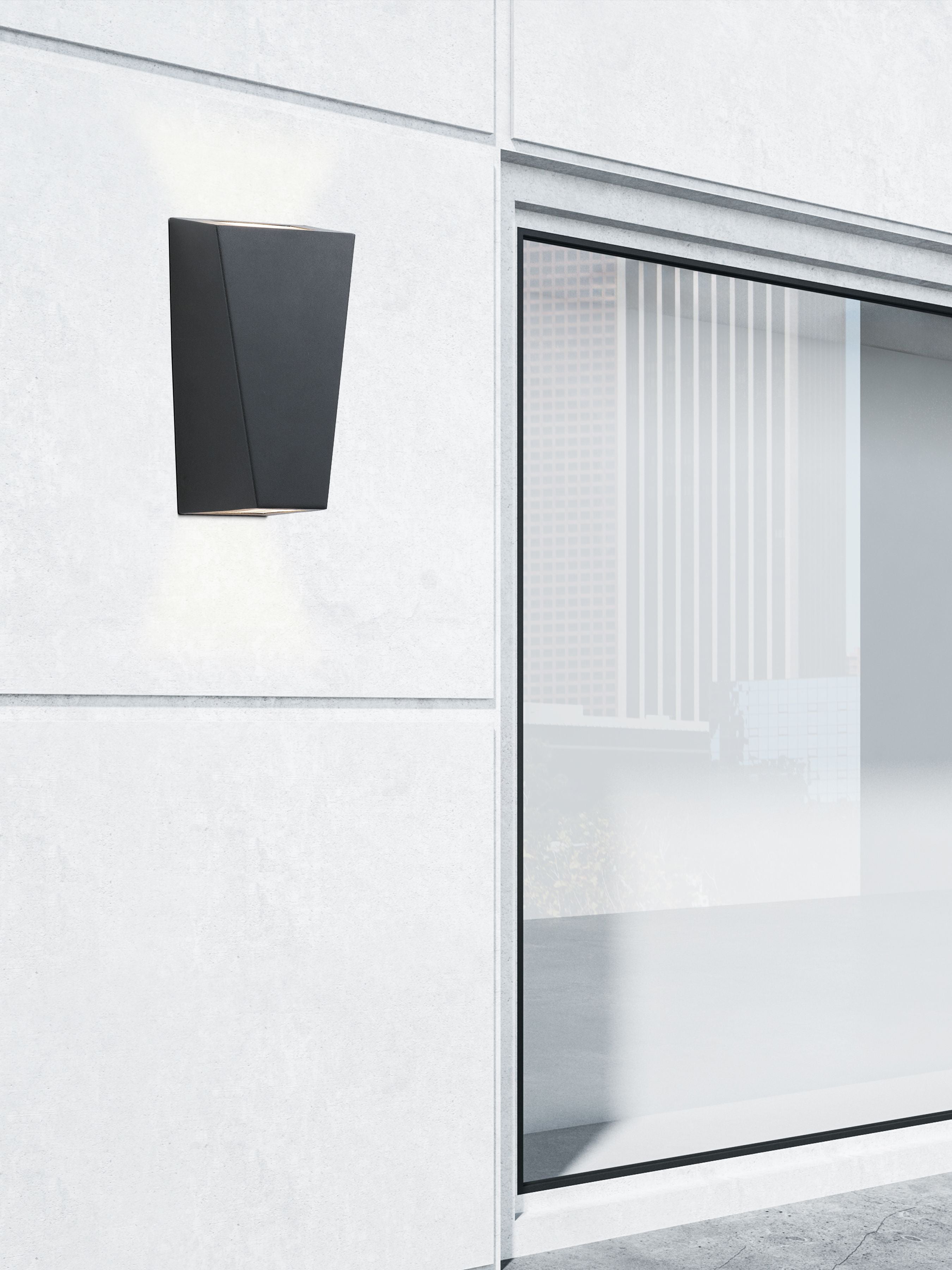 Sheffield outdoor wall light fitted to a concrete exterior wall in daylight, lit, next to a glass shopfront window
