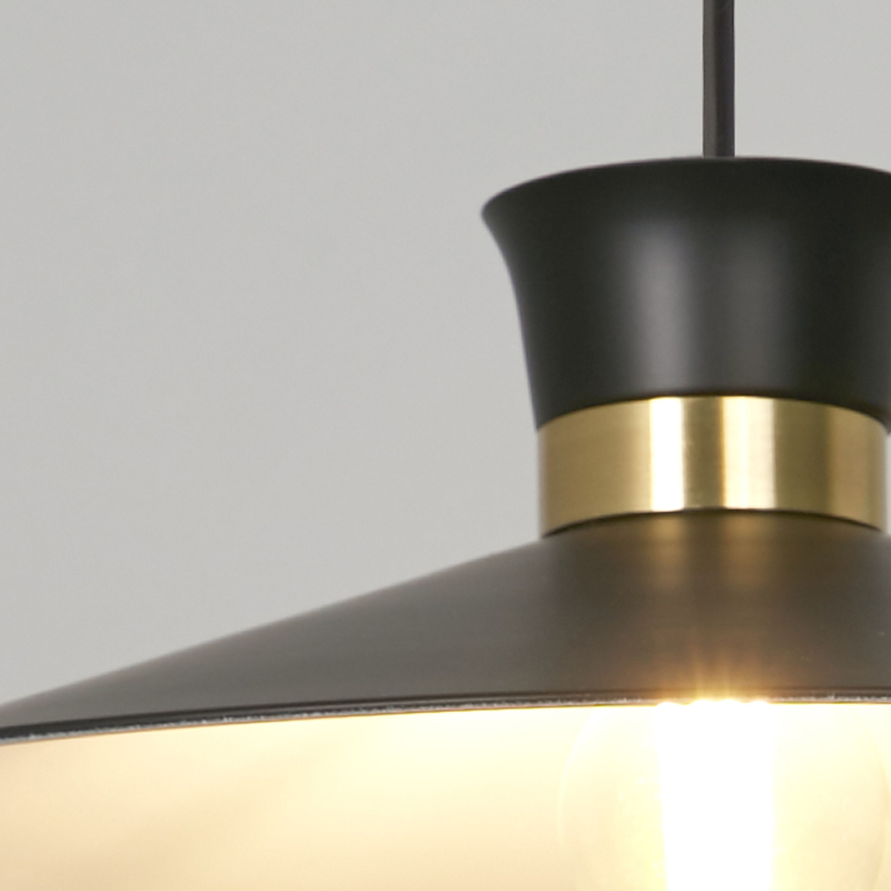 Close up of the Searchlight Balham pendant's satin brass neck band, showing where it meets the matt black shade and fitting