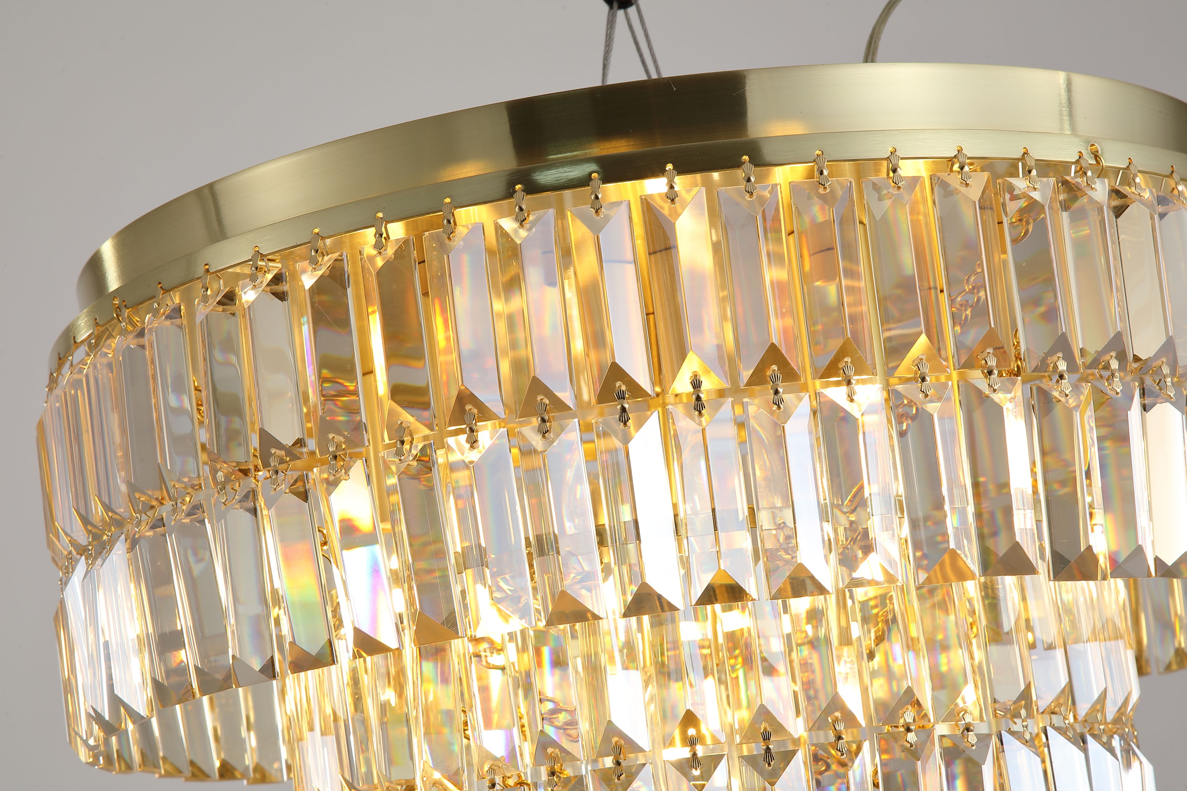 Close up of the Empire flush light's champagne glass tiers and satin brass frame, showing the faceted crystal detail lit from within