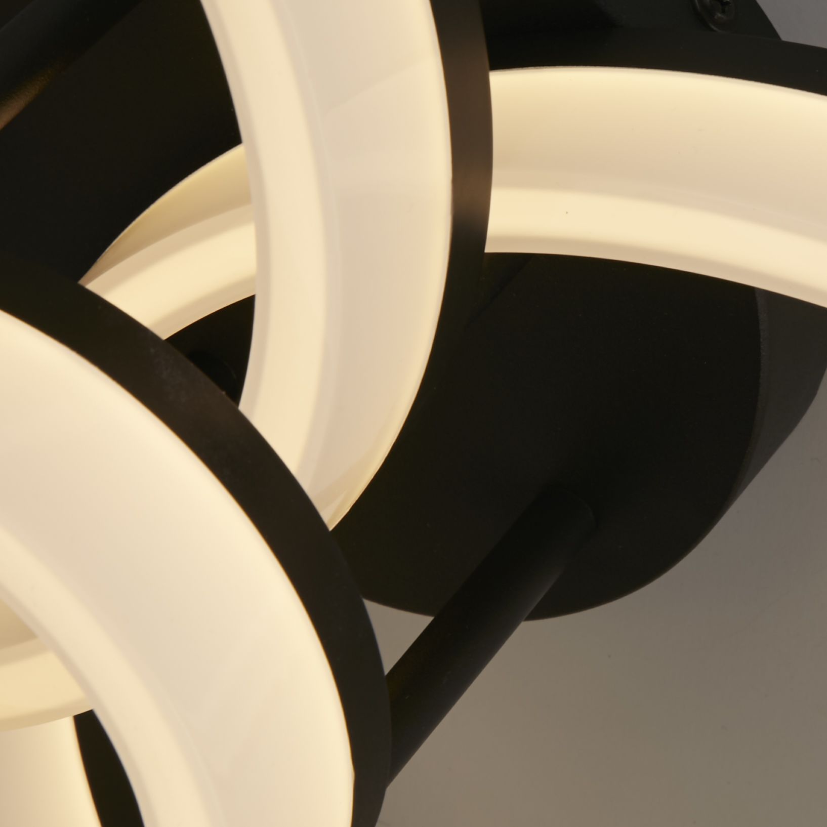 Close up detail of the Searchlight Triple LED Flush ceiling light showing the black frame and warm white glow where the rings overlap