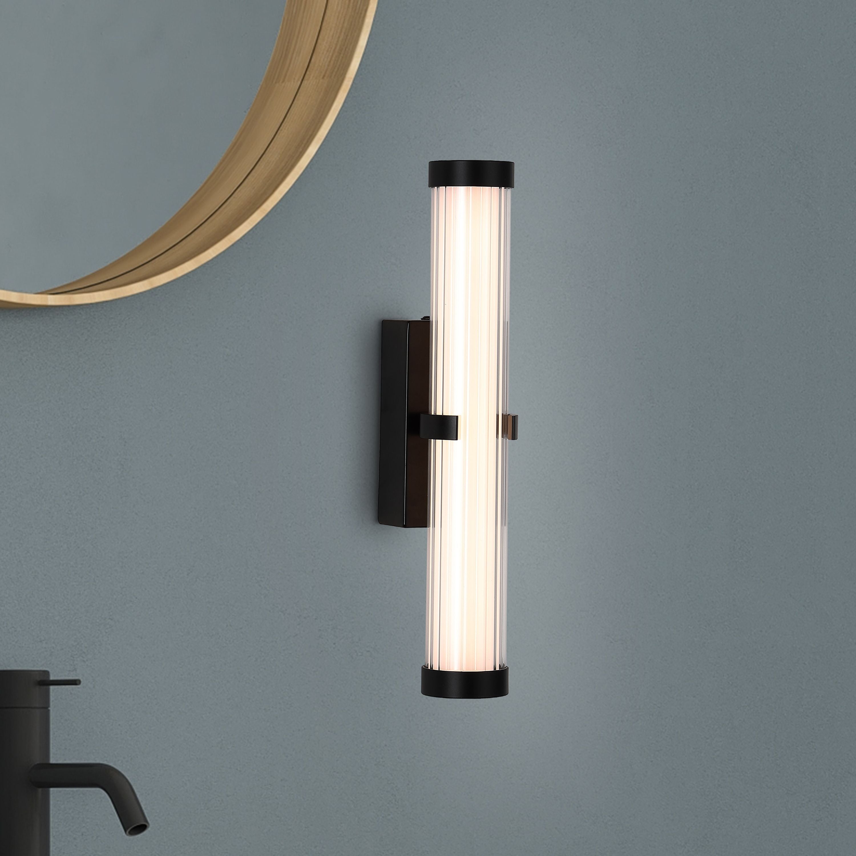 Searchlight Clamp wall light in black mounted beside a round wood framed mirror above a bathroom sink with black tap