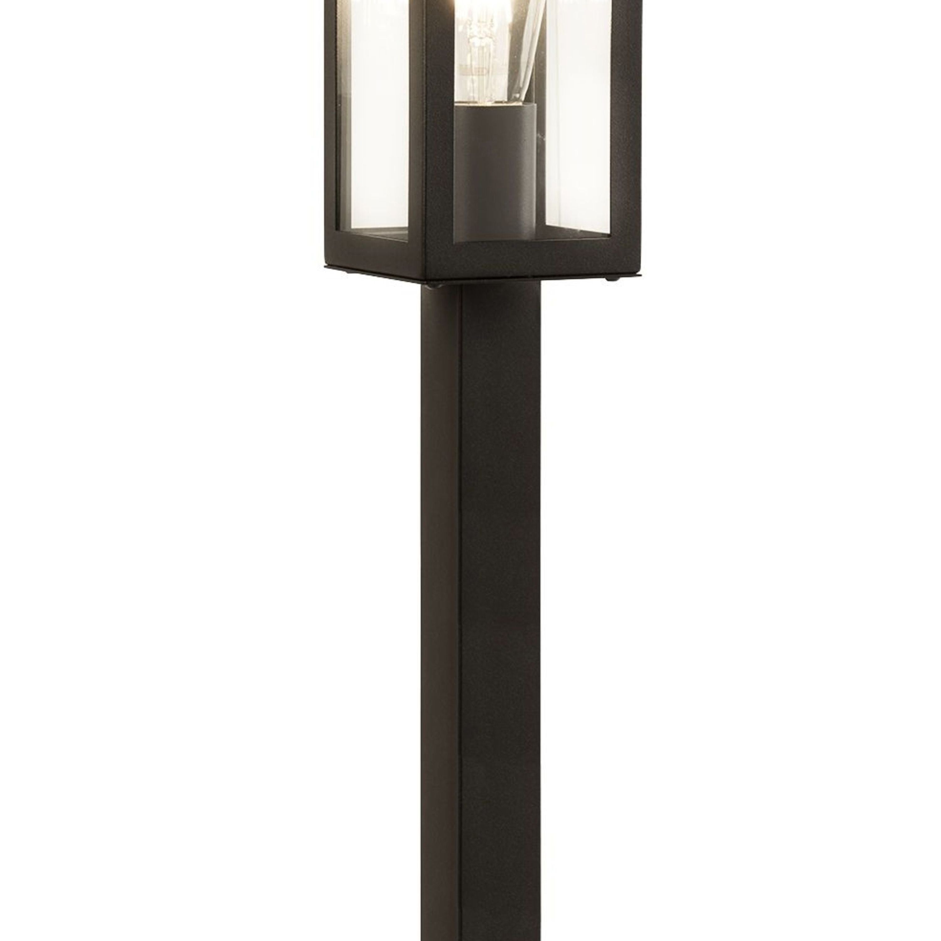 Close up of the Box outdoor post light's glazed head showing the exposed filament style bulb through the clear glass panel and black frame