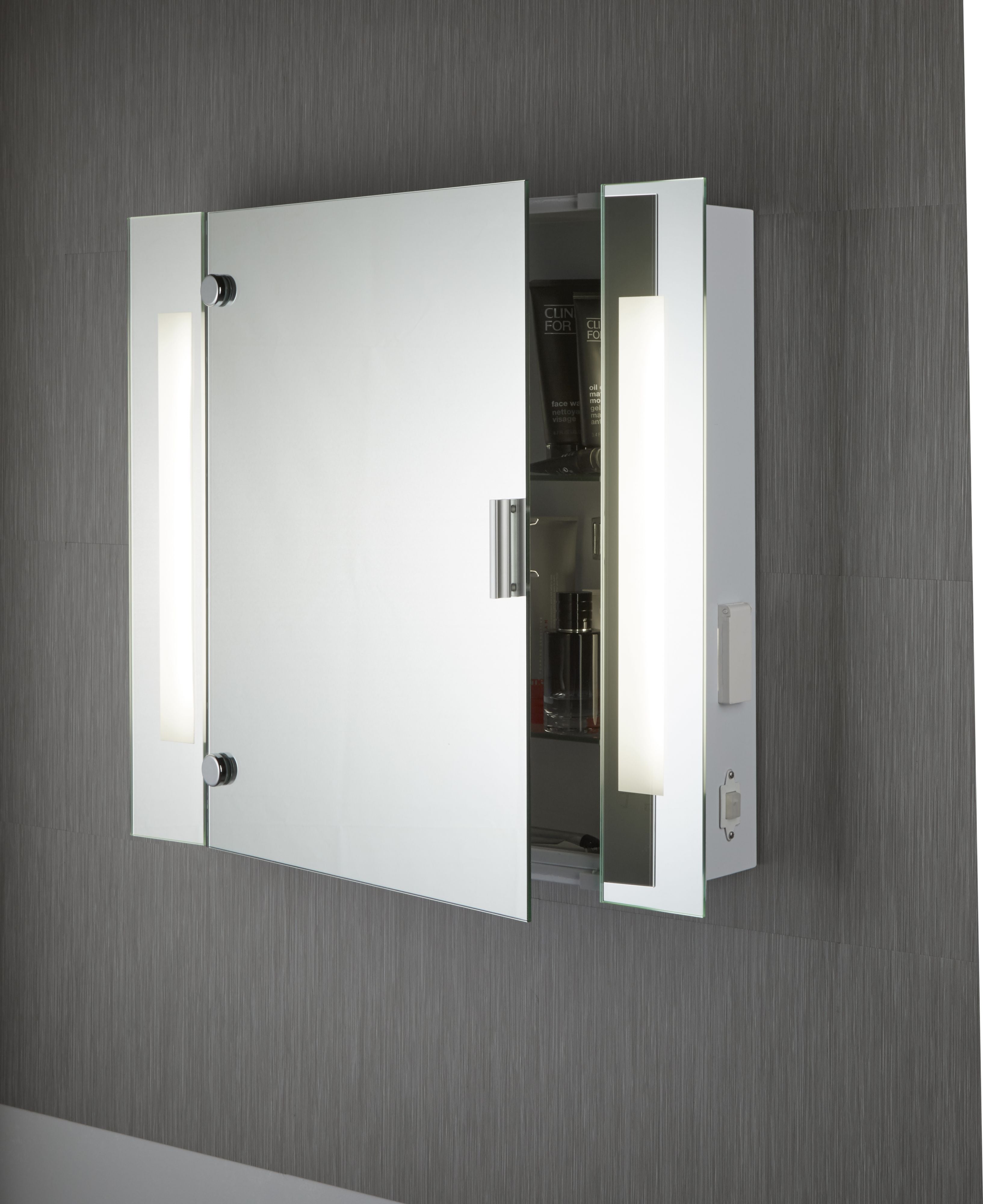 Searchlight mirror cabinet wall mounted on a dark tiled wall with the door ajar, side light strips lit and toiletries visible on the interior shelf
