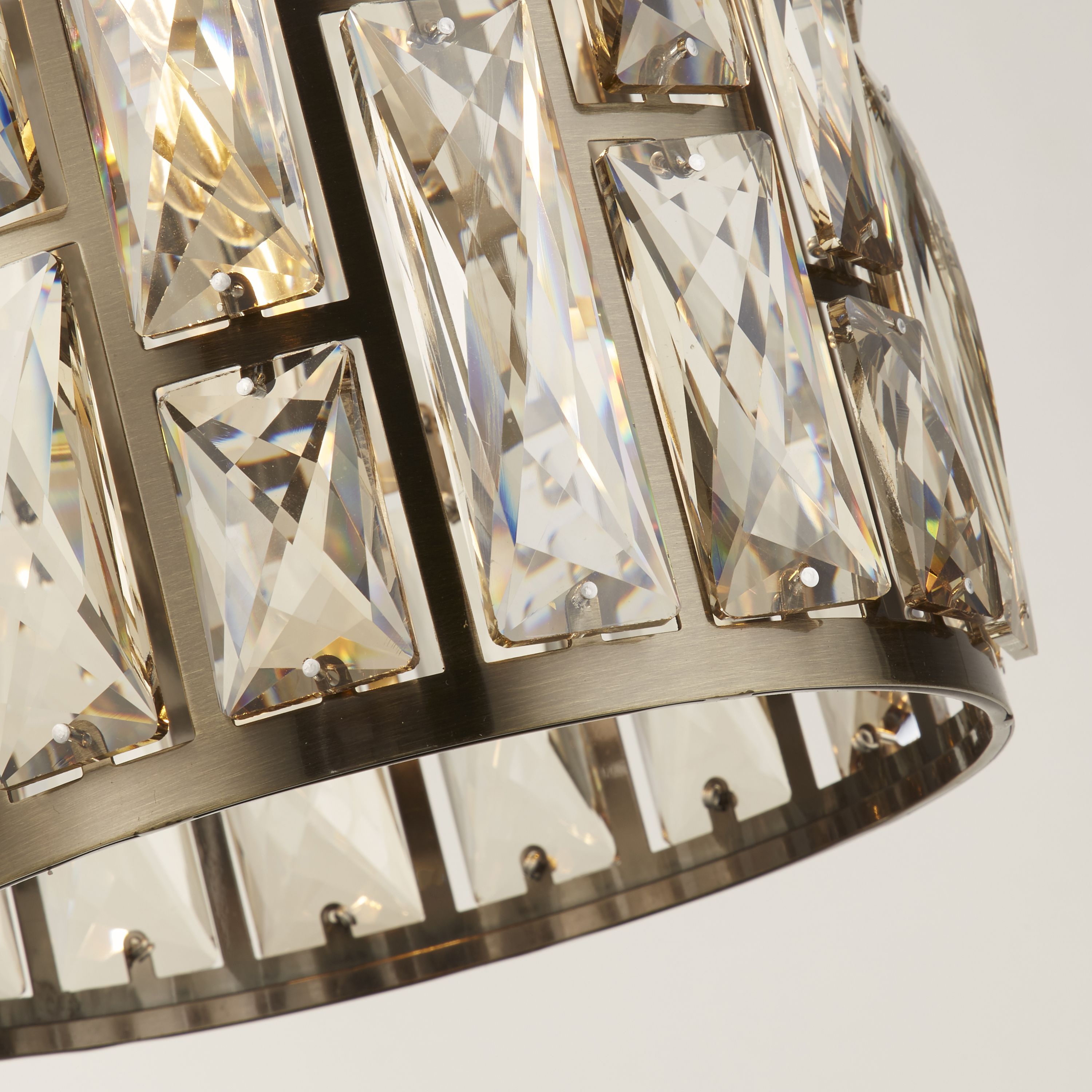 Close up of the Bijou pendant's champagne glass baguettes set in an antique brass frame, showing the faceted cut detail