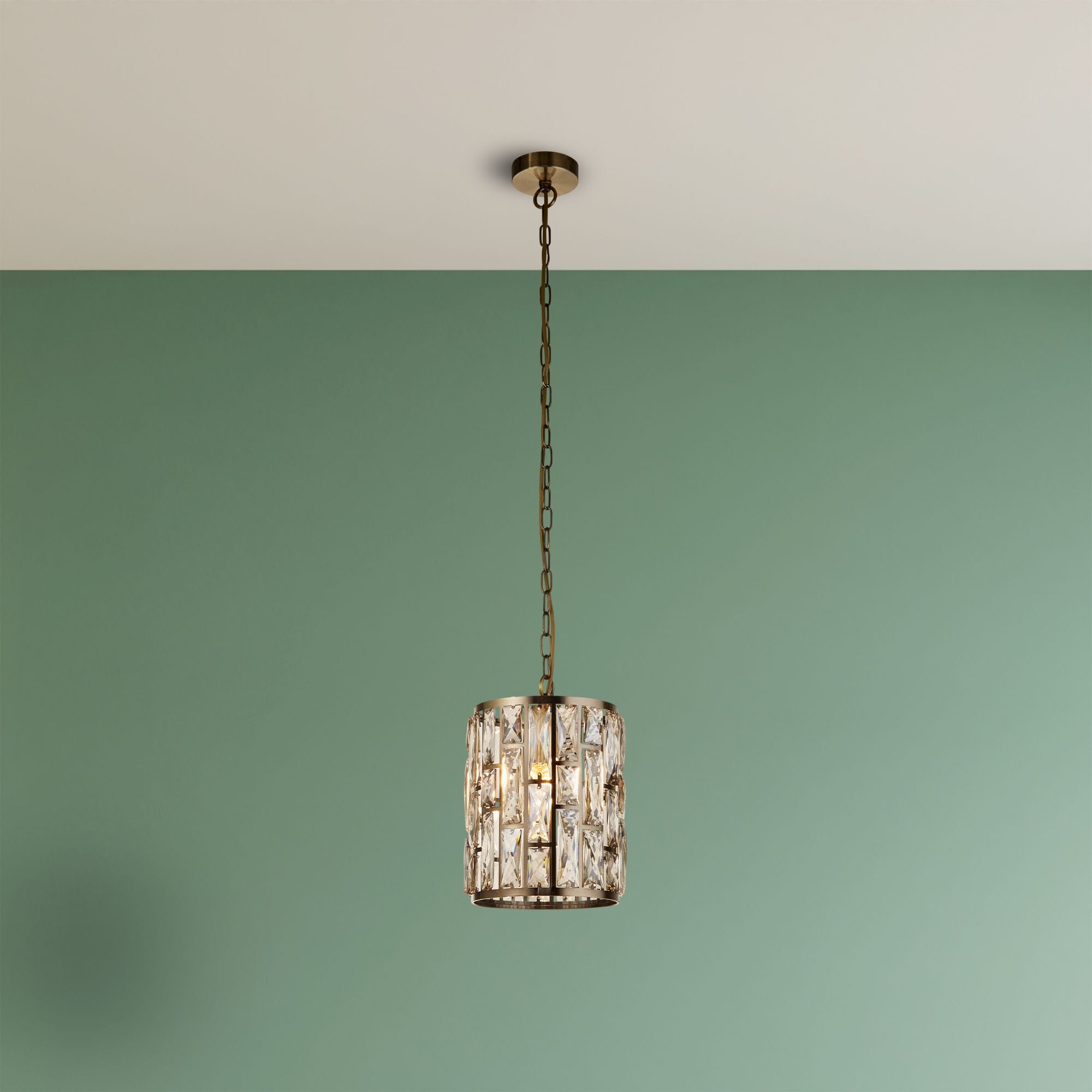 Searchlight Bijou pendant in antique brass and champagne glass hanging in a styled living room against a two tone sage green and white wall