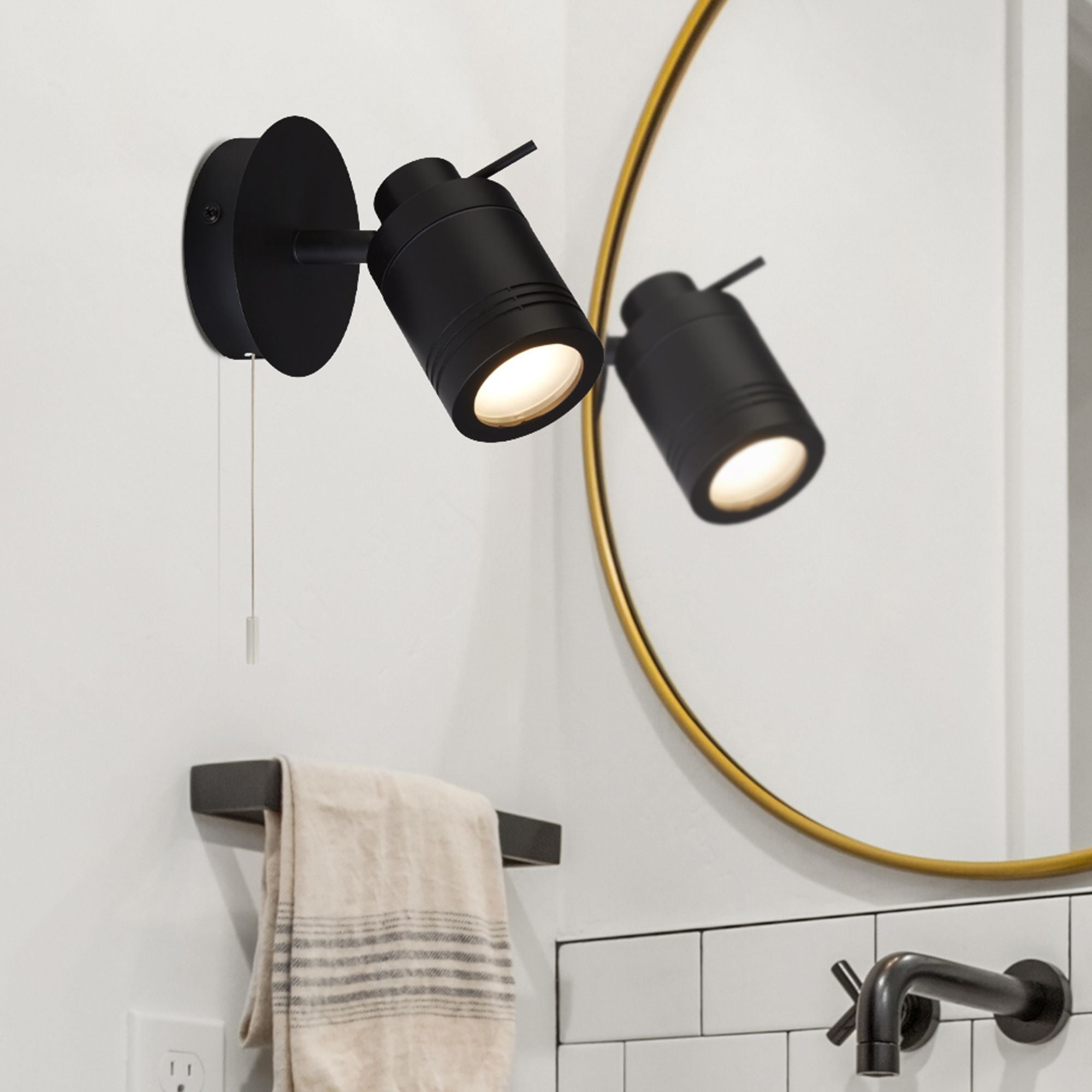Searchlight Samson spotlight installed beside a bathroom mirror with a gold frame, towel rail and tap in view