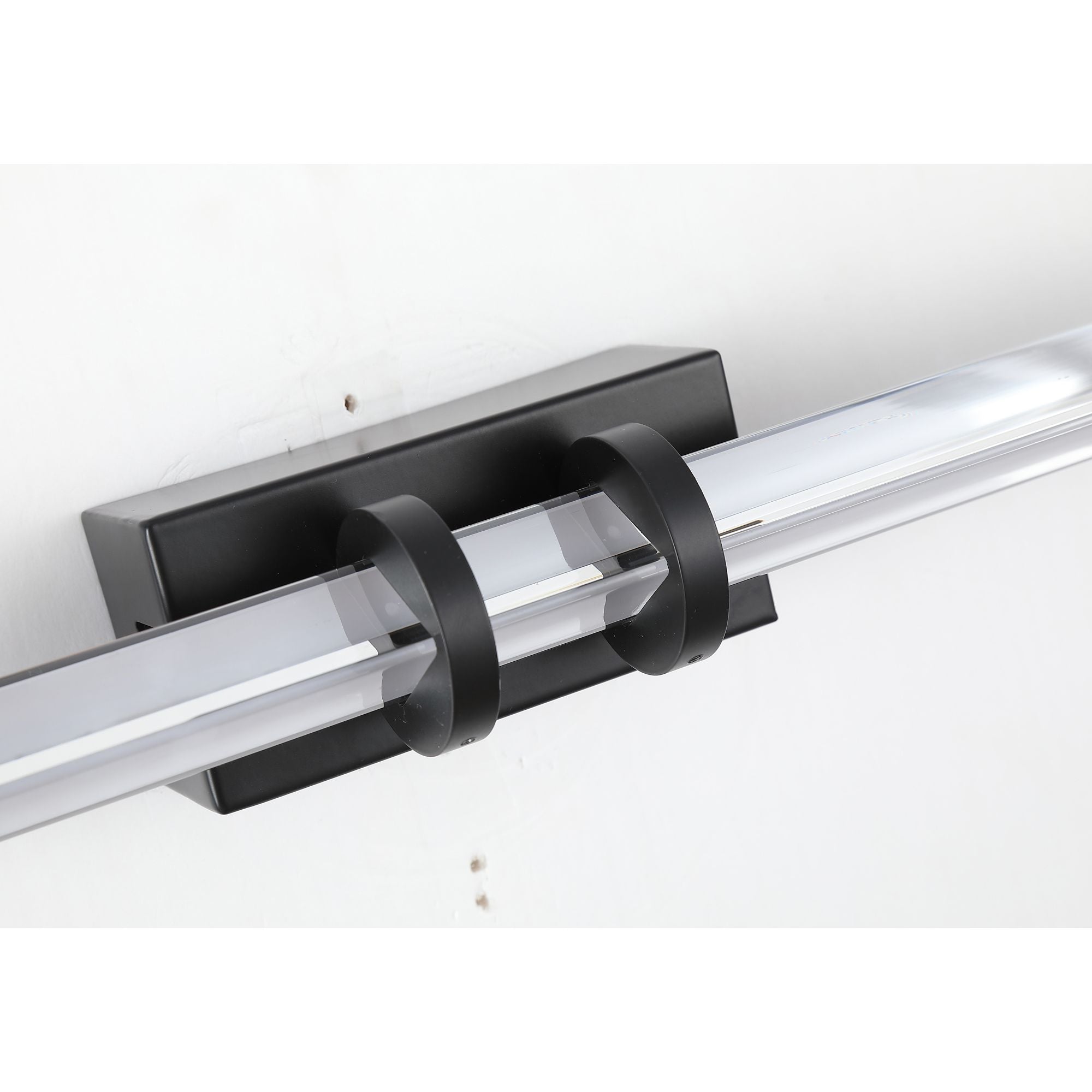 Close up angled view of the Searchlight Parma LED wall light showing the matt black central bracket and the faceted clear glass bars