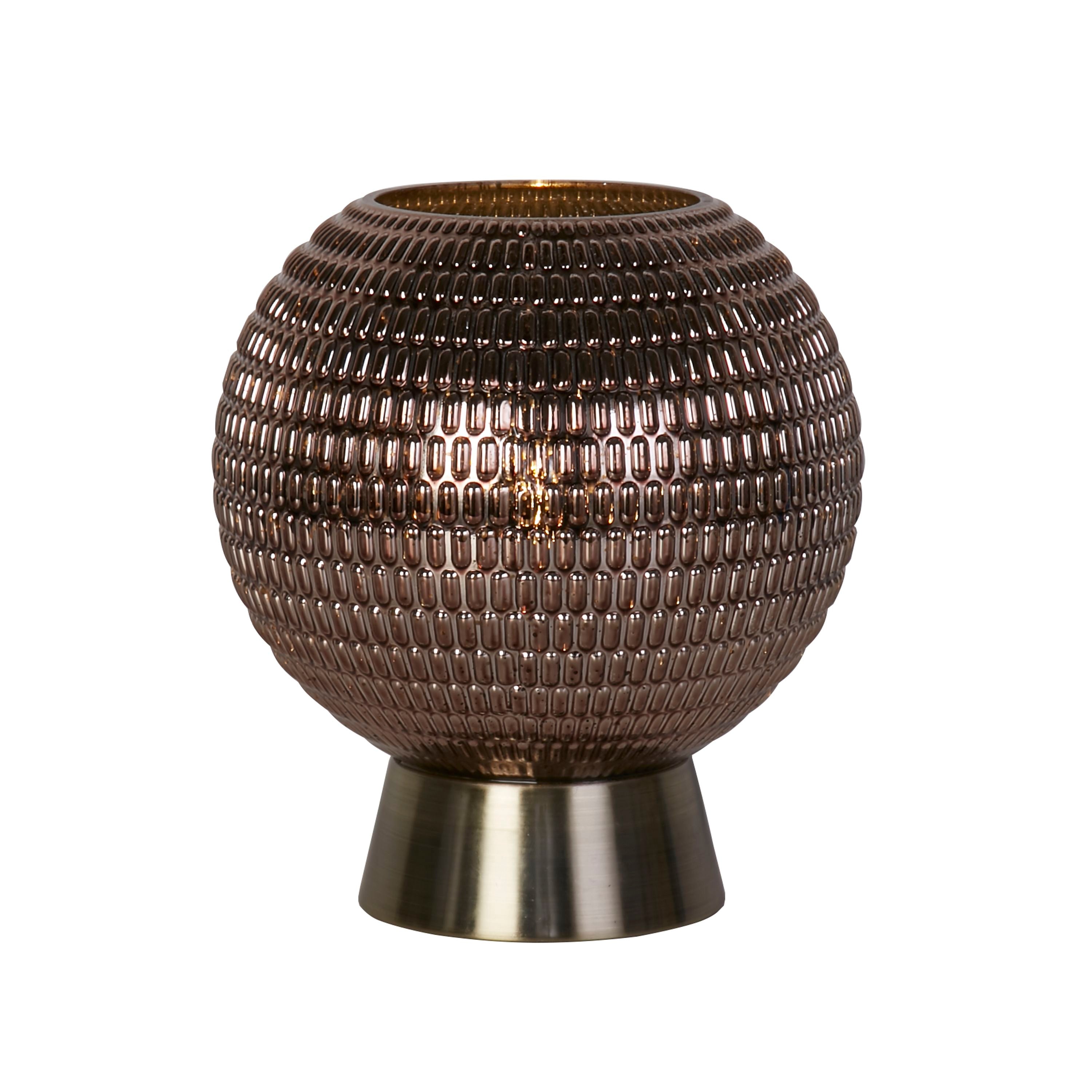 Searchlight Mila table lamp, a round textured brown glass globe on an antique brass foot, lit, studio shot on a white background