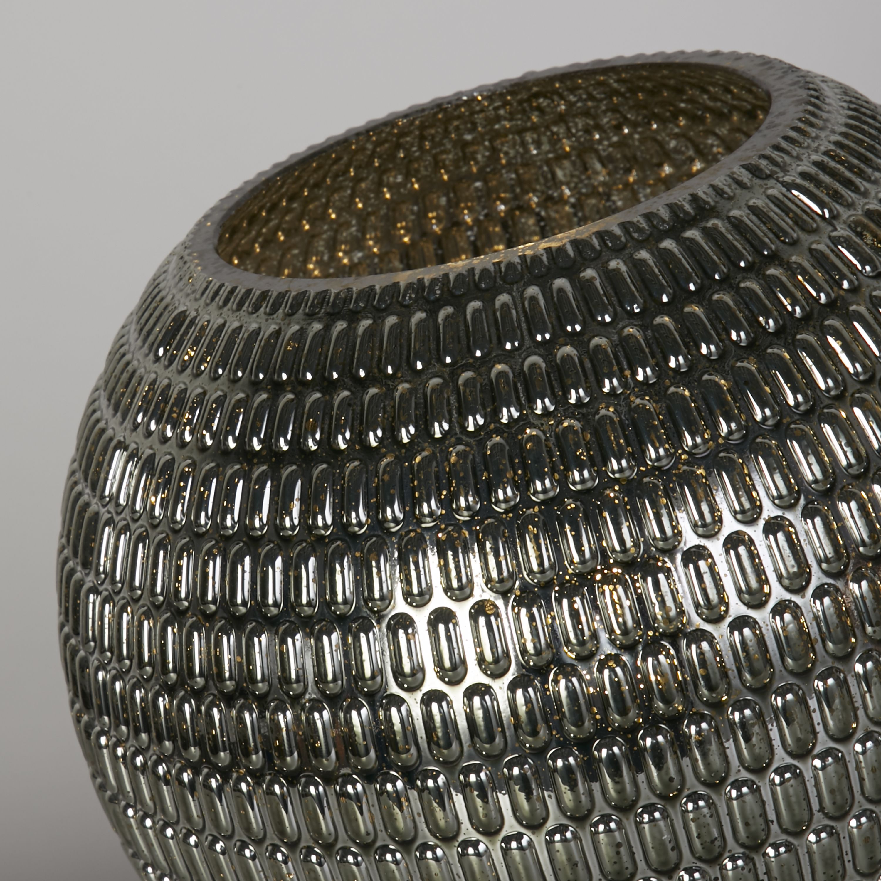 Close up of the Mila lamp's dimpled glass texture, showing the oval reeded pattern in green glass with gold flecks and the brass rim