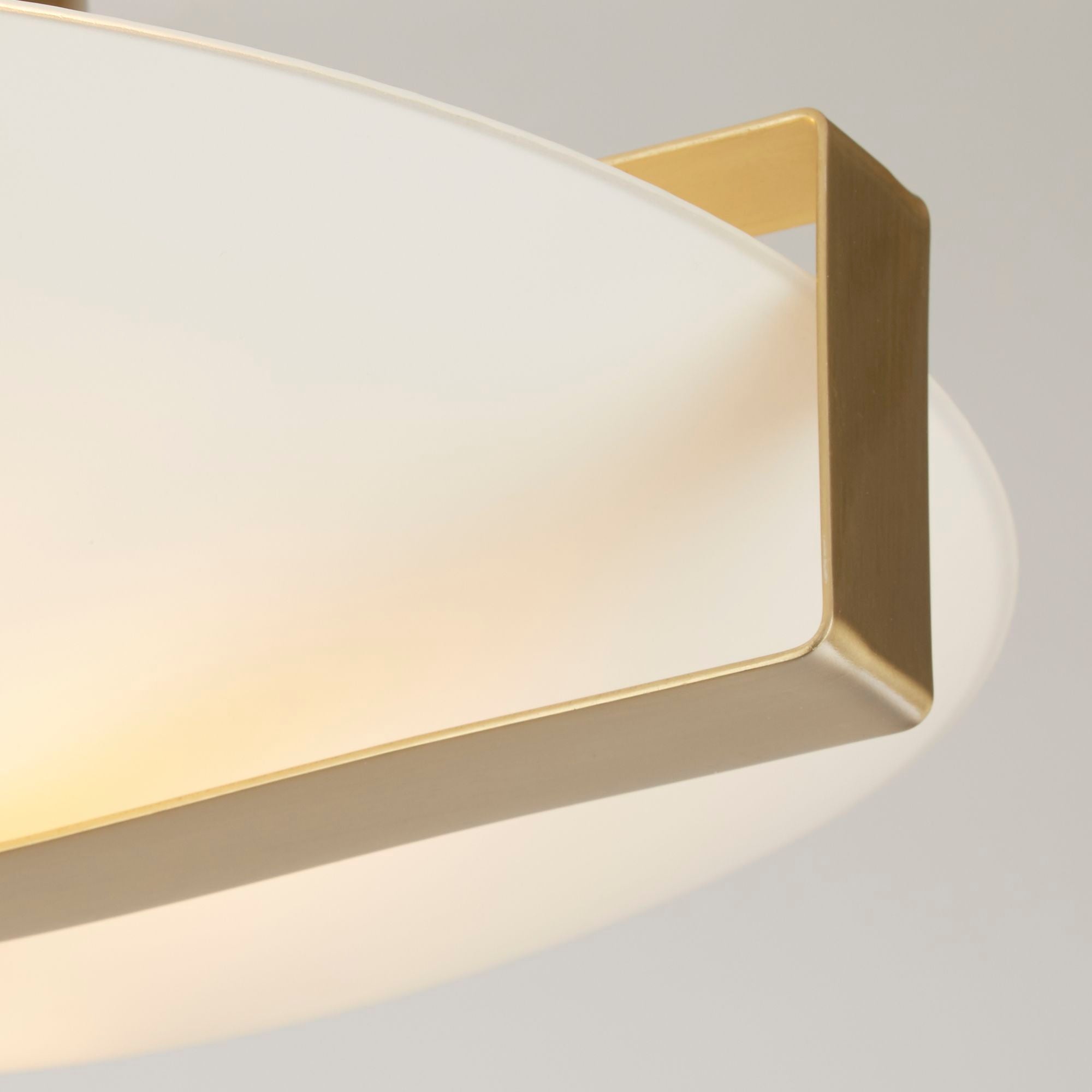 Close up of the gold bracket and diagonal bar detail on the Searchlight Sundial flush ceiling light frosted glass shade