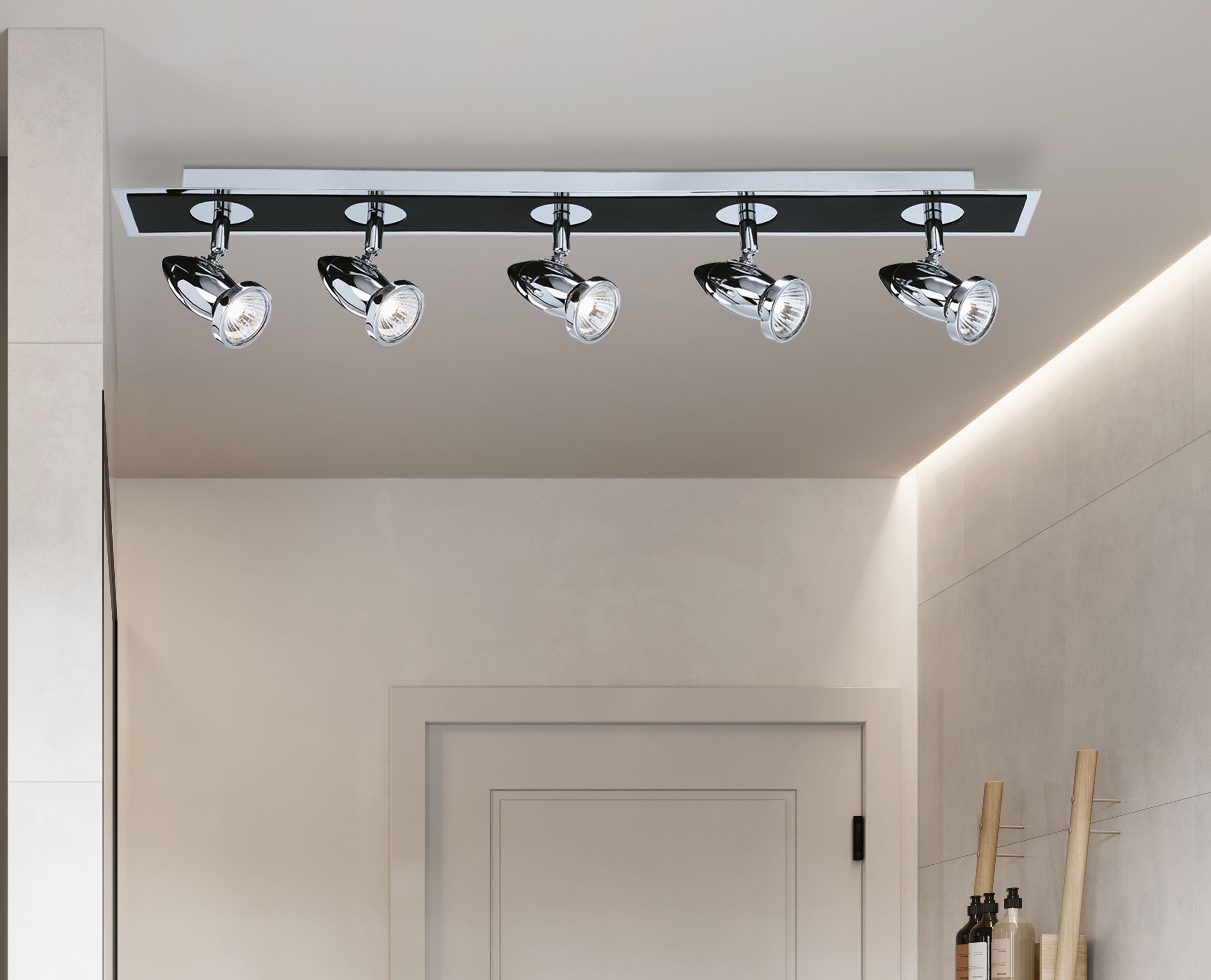 Searchlight Comet 5 light bar spotlight in matt black and polished chrome mounted in a hallway above a wooden door, lights on