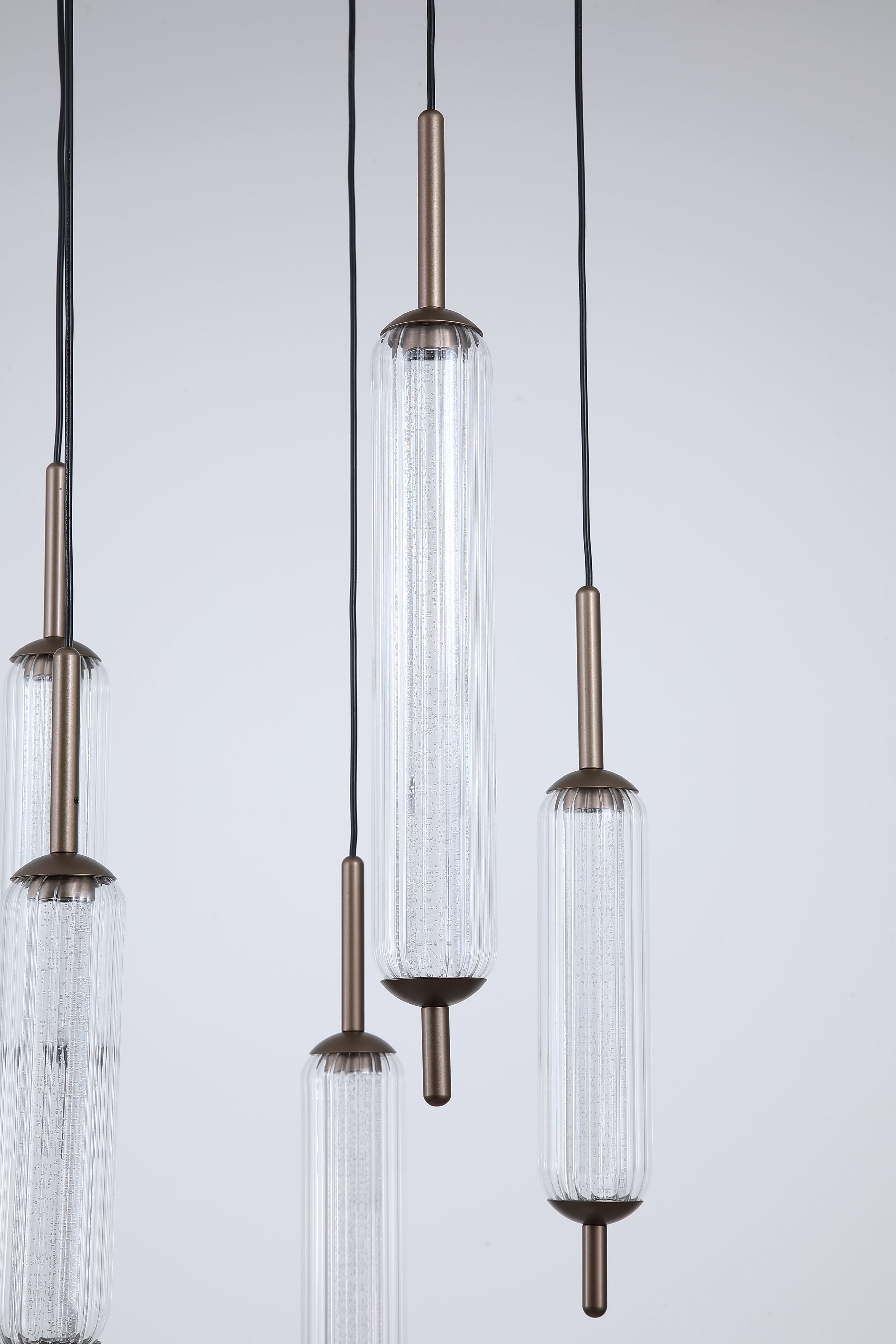 Close up of three Cattail pendant cylinder shades, showing the ribbed clear glass and bronze metal caps