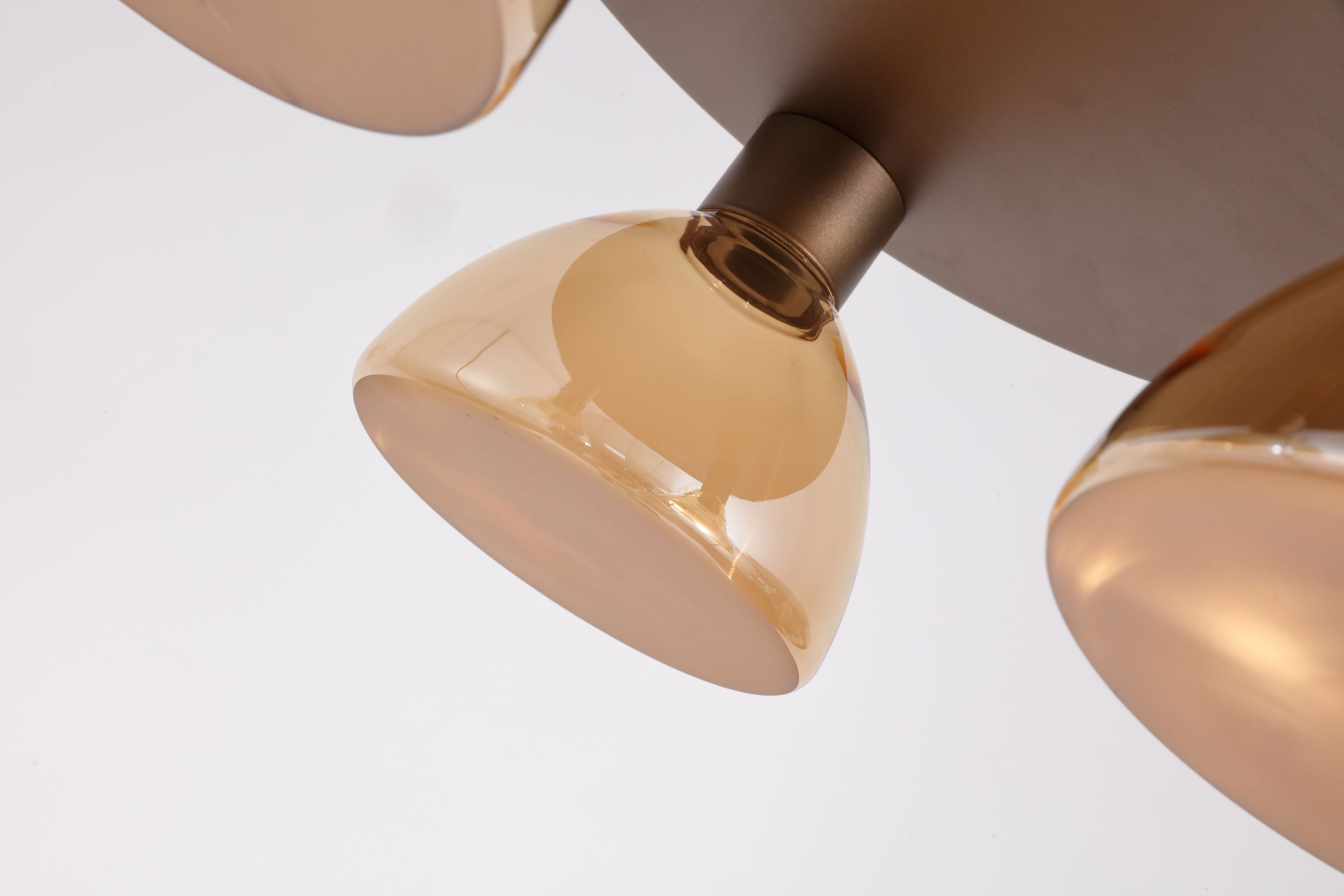 Close up of one amber glass dome shade on the Searchlight Cannes Flush, showing the latte bronze lampholder and the shade's rounded profile