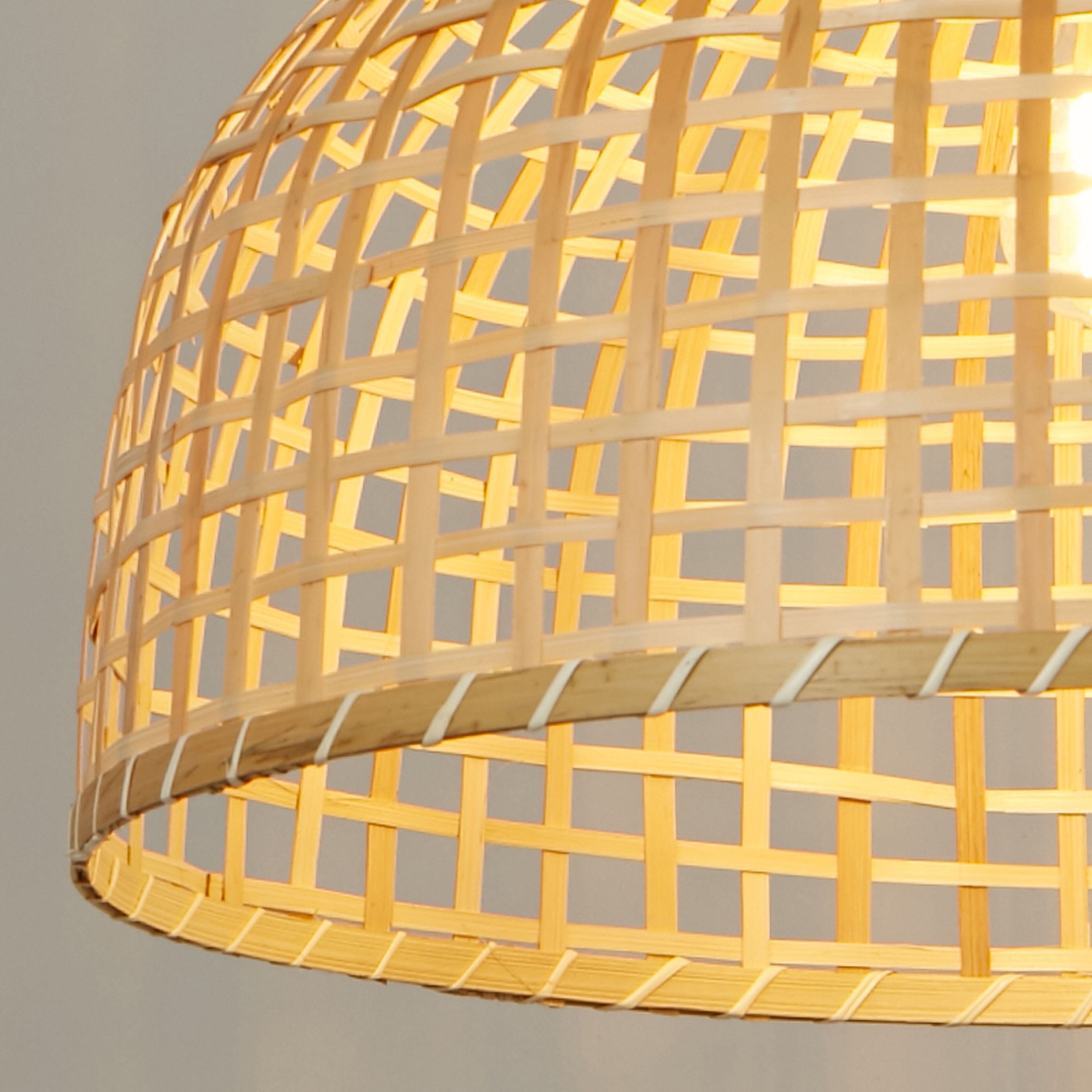 Close up of the Bali Pendant's bamboo weave, showing the crossed strip pattern and the lit bulb glowing through the open lattice