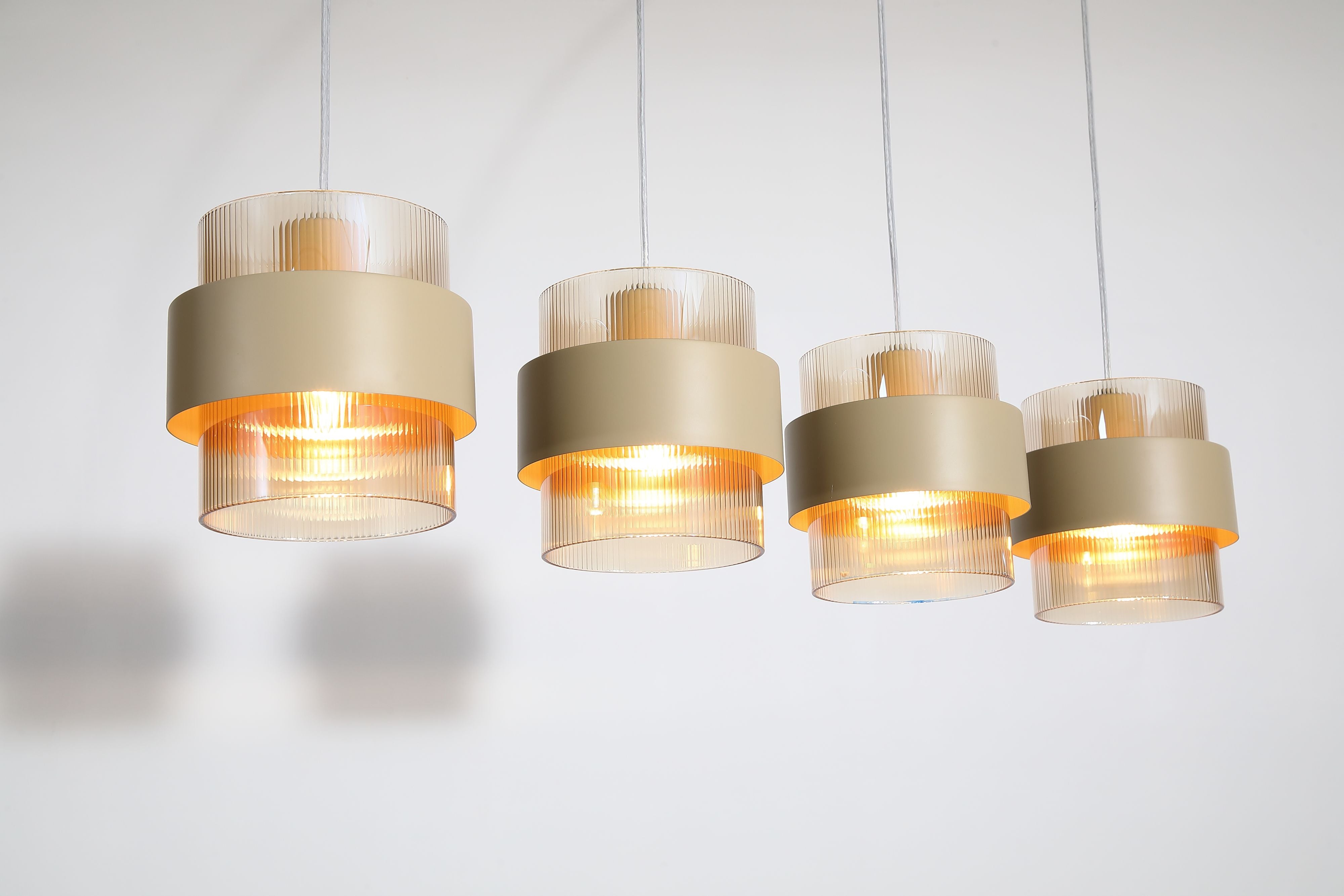 Close up of the Searchlight Royal 4 Light Bar Pendant showing four ribbed amber glass shades lit along the bar
