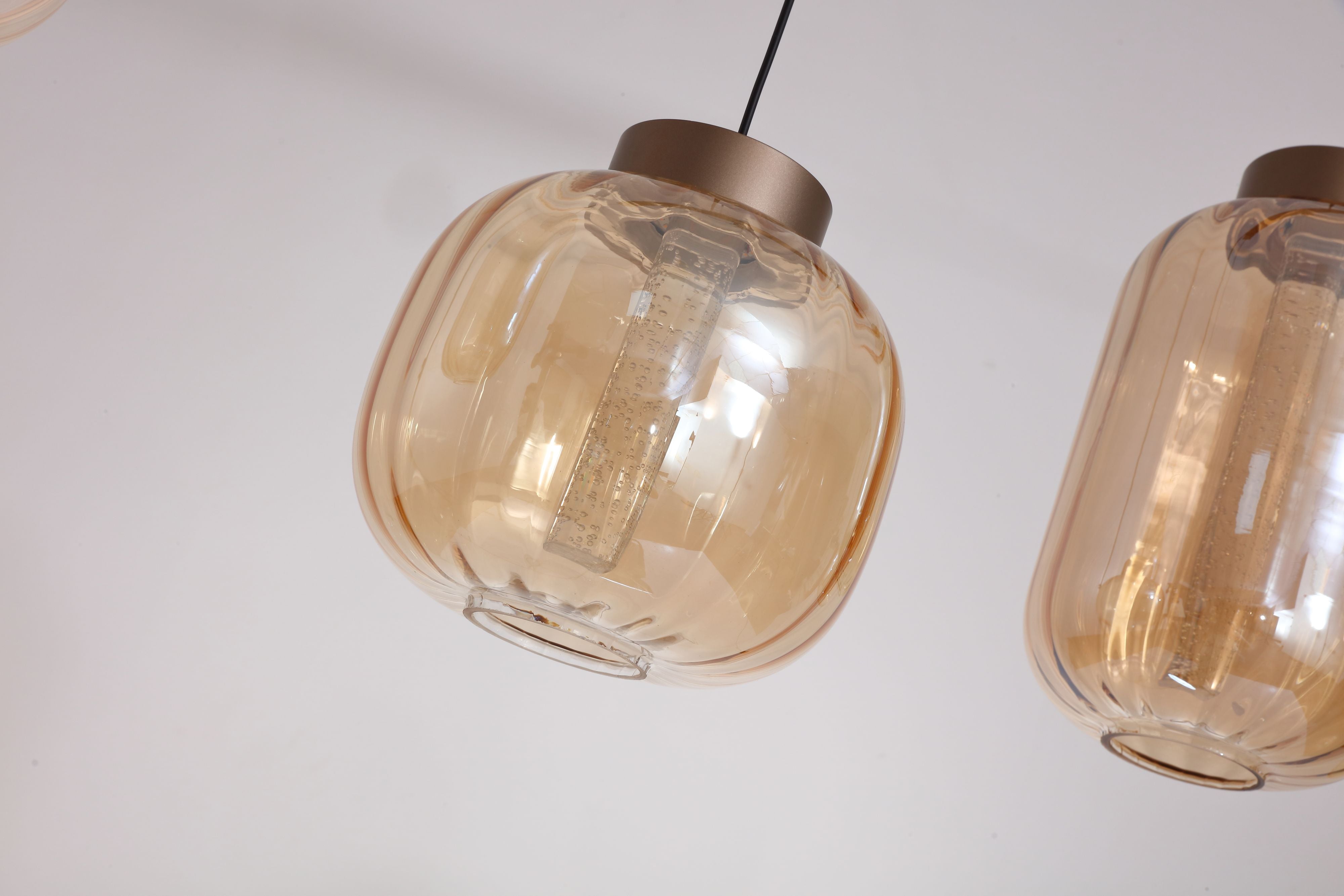 Close up of the ribbed amber glass shade on the Searchlight Lille pendant, showing the integrated LED strip and latte bronze shade cap