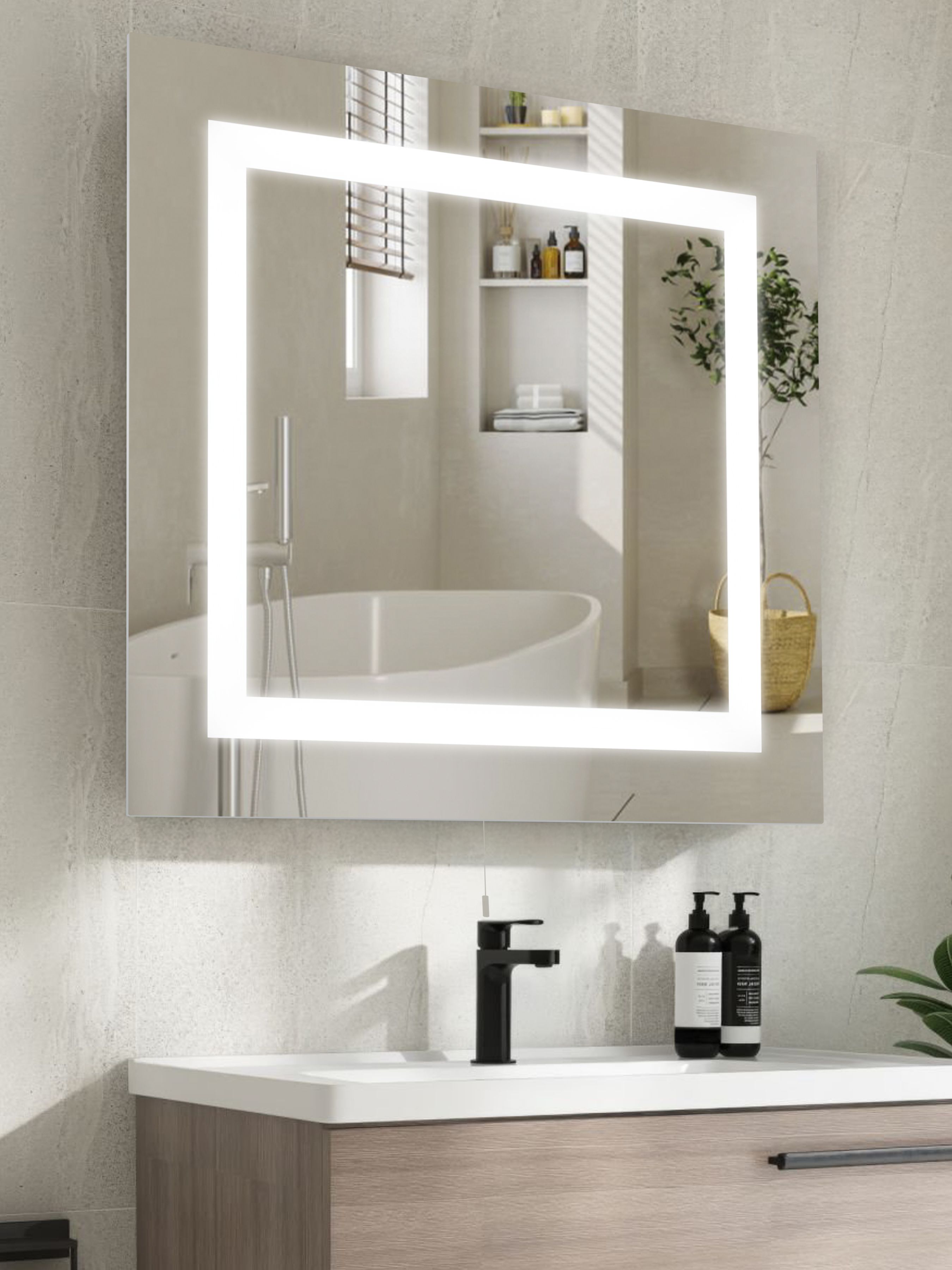 Searchlight rectangular mirror styled above a vanity unit in a stone finished bathroom, frosted border lit, reflecting a freestanding bath