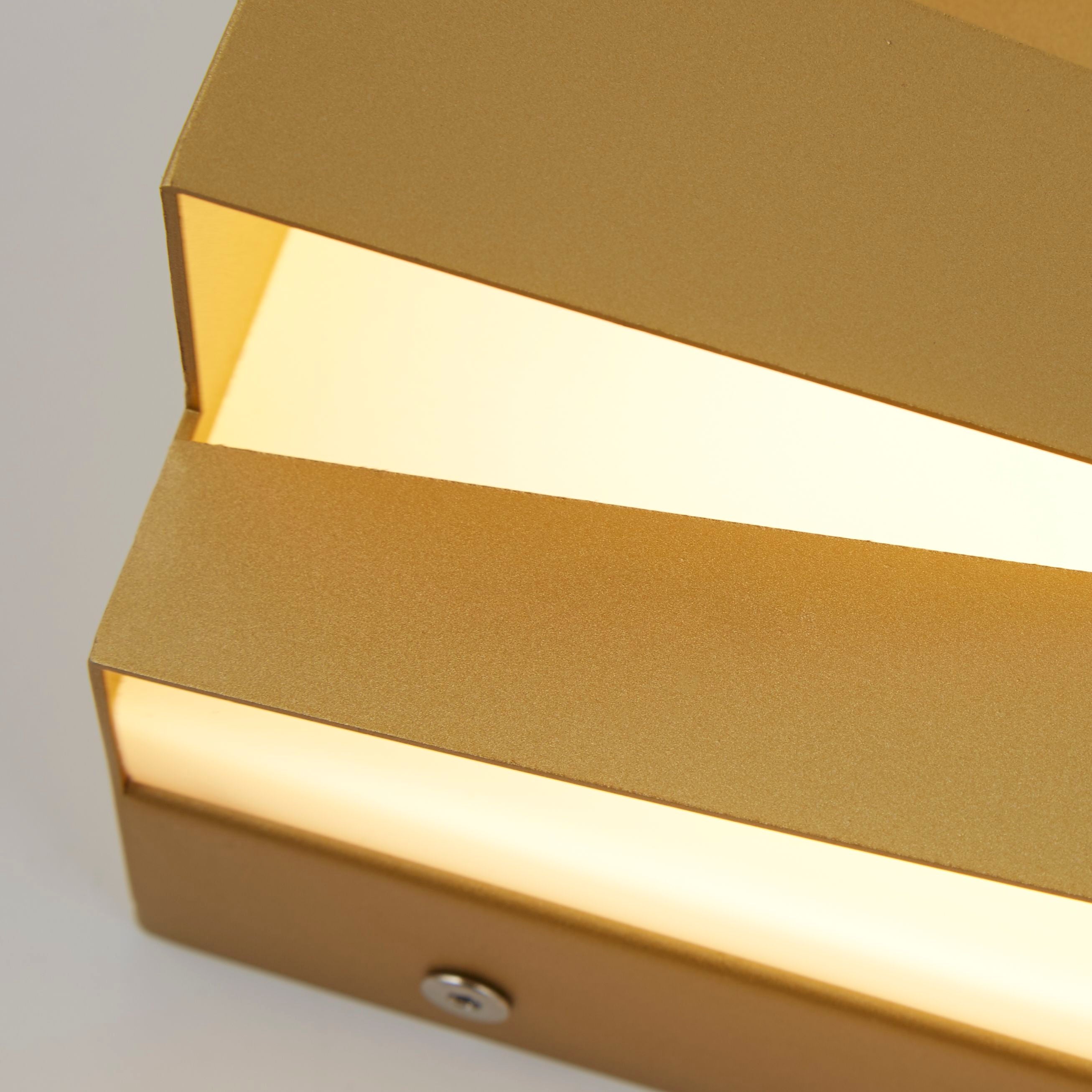 Close up detail of the Section wall light's sand gold iron frame and acrylic diffuser strips, showing the fixing screw