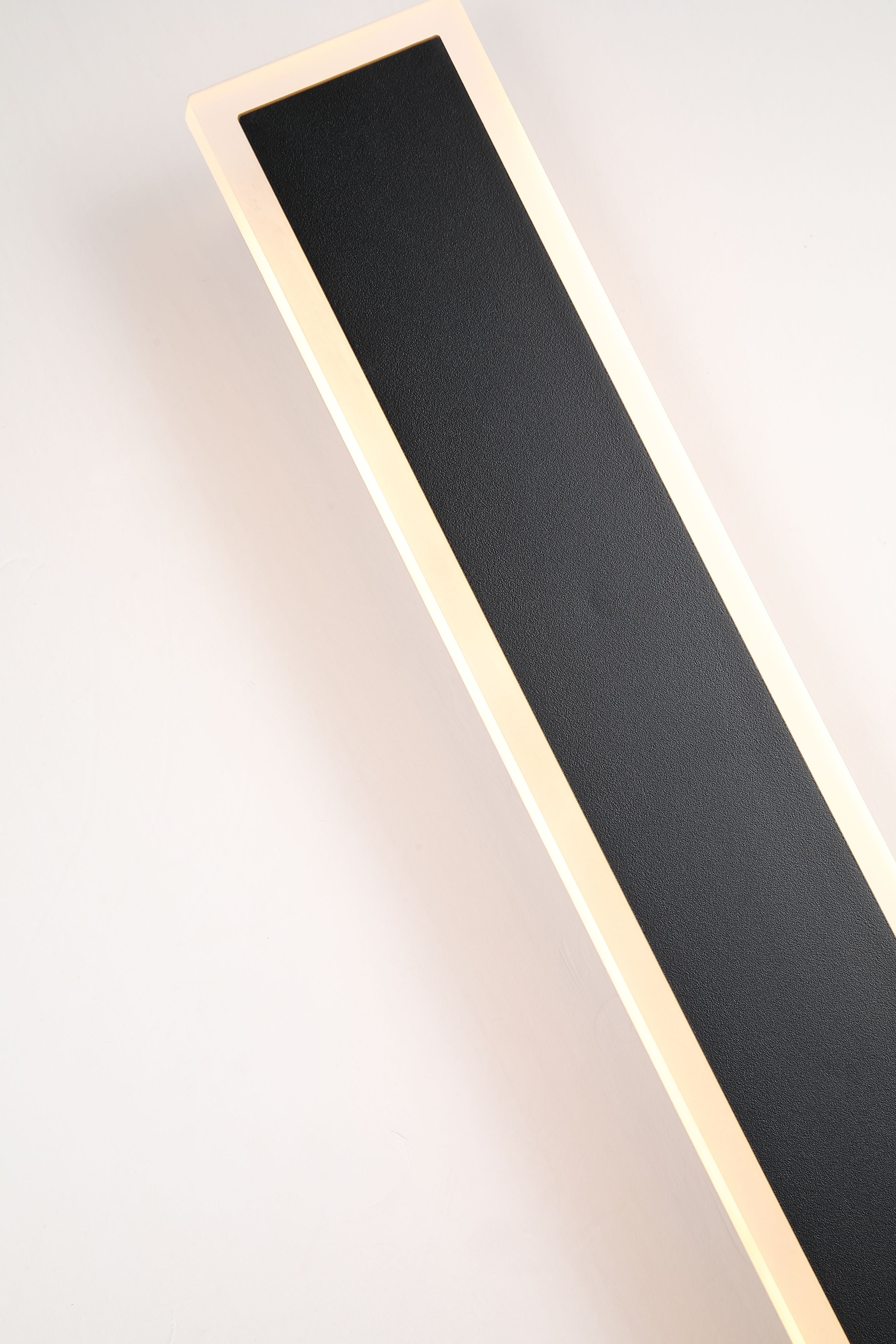 Close up angled view of the Bordo II Square wall light lit, showing the textured black finish and glowing acrylic edge strip