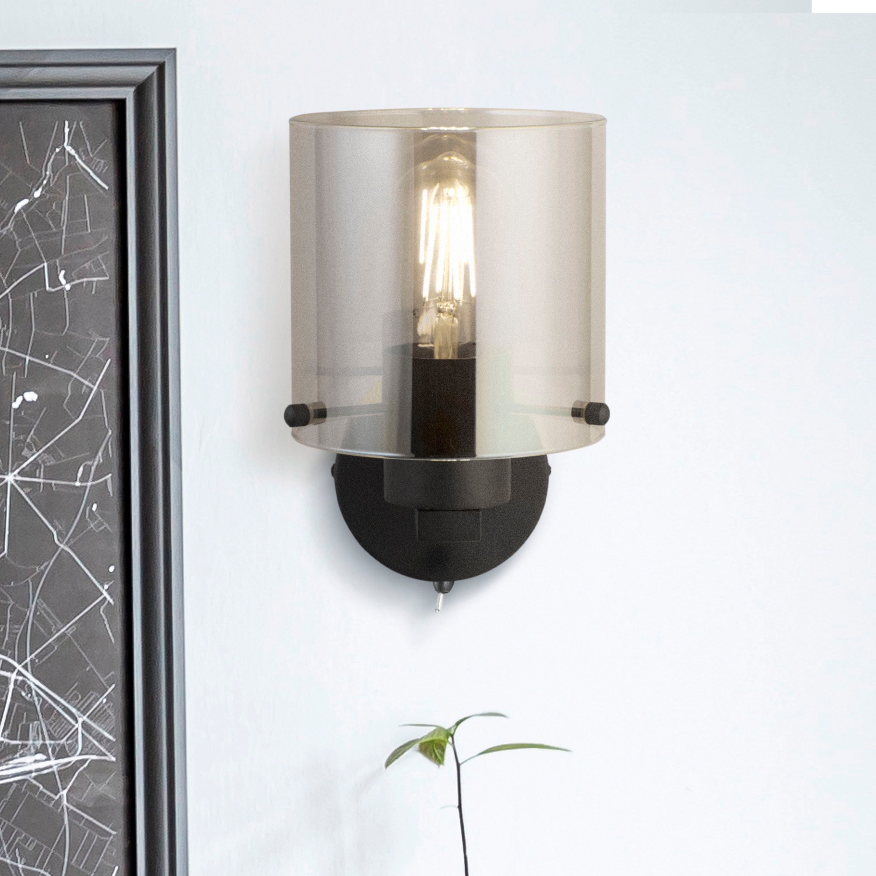 Searchlight Sweden 1 Light Wall Light in matt black with smoked glass, styled on a wall beside a framed map print and a small plant