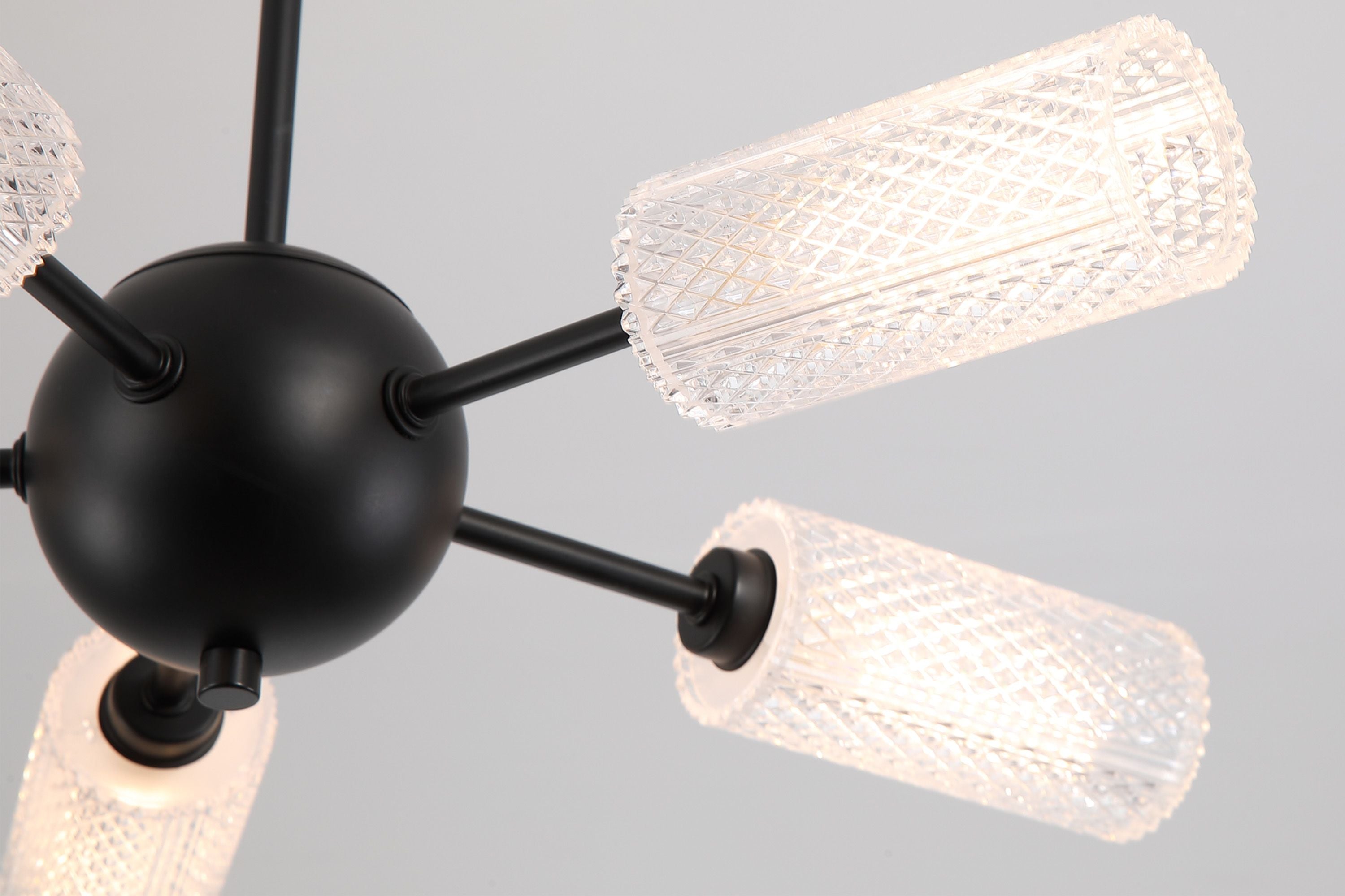 Close up of the black iron sphere and textured acrylic shades on the Cosmic 5 light ceiling fitting, showing the faceted glass detail