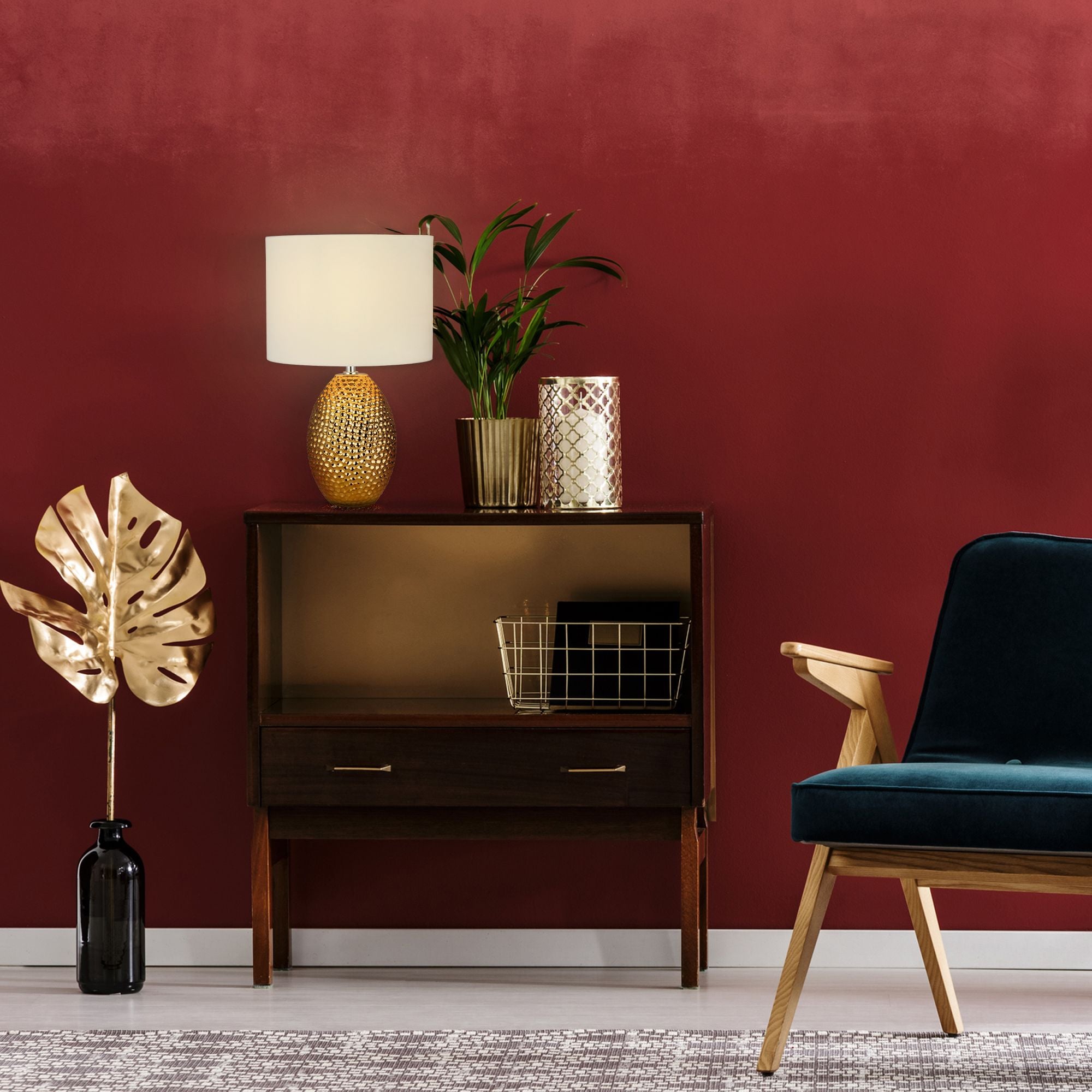 Nadine table lamp styled on a dark wood sideboard against a deep red wall, with a plant and gold accessories
