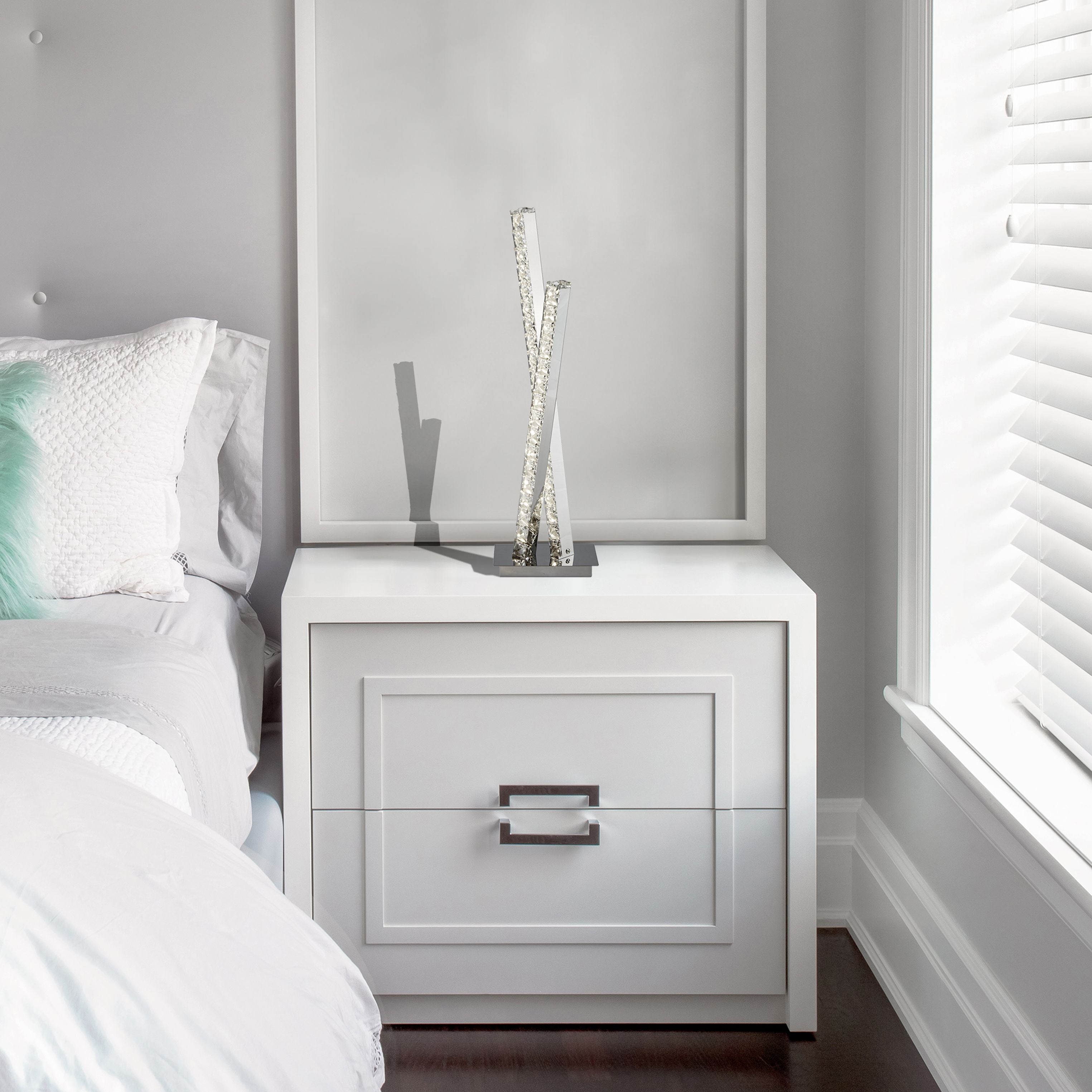 Clover table lamp in chrome and crystal styled on a white bedside cabinet next to a framed print