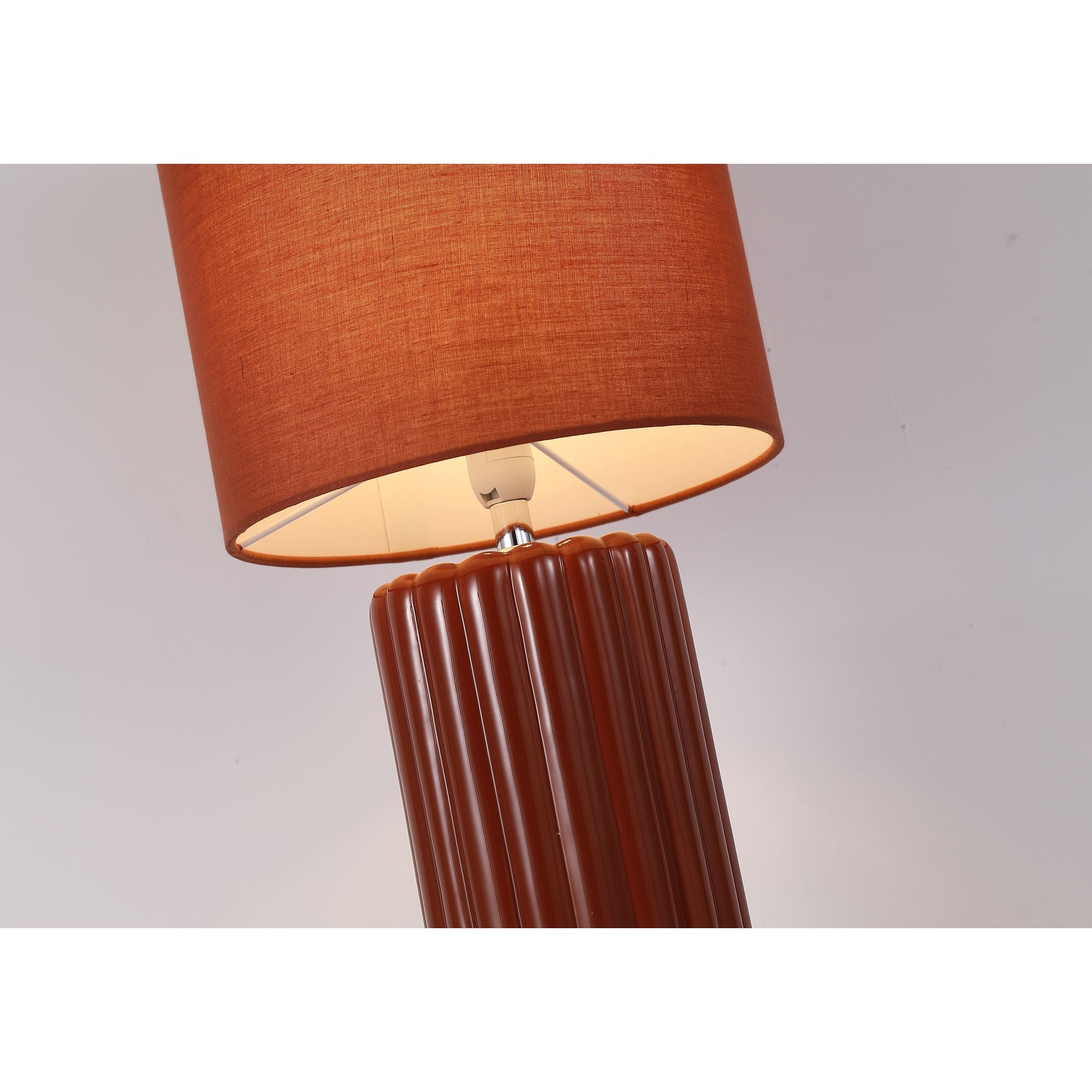 Close up angled view of the Groove burnt orange table lamp, showing the fluted ceramic neck and the inside of the fabric drum shade