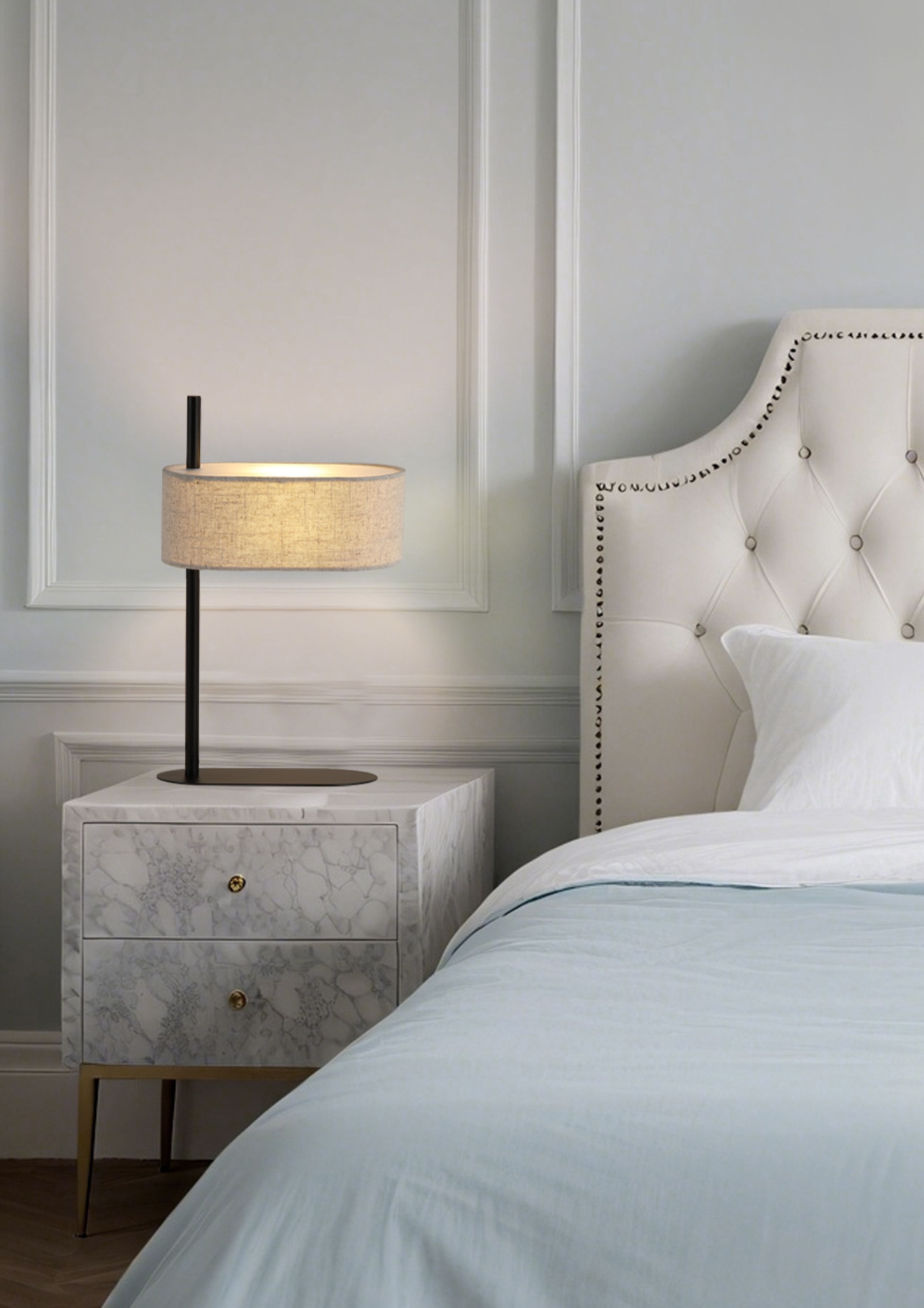 Searchlight Hessian table lamp switched on beside a bed, standing on a marble bedside cabinet in a styled bedroom