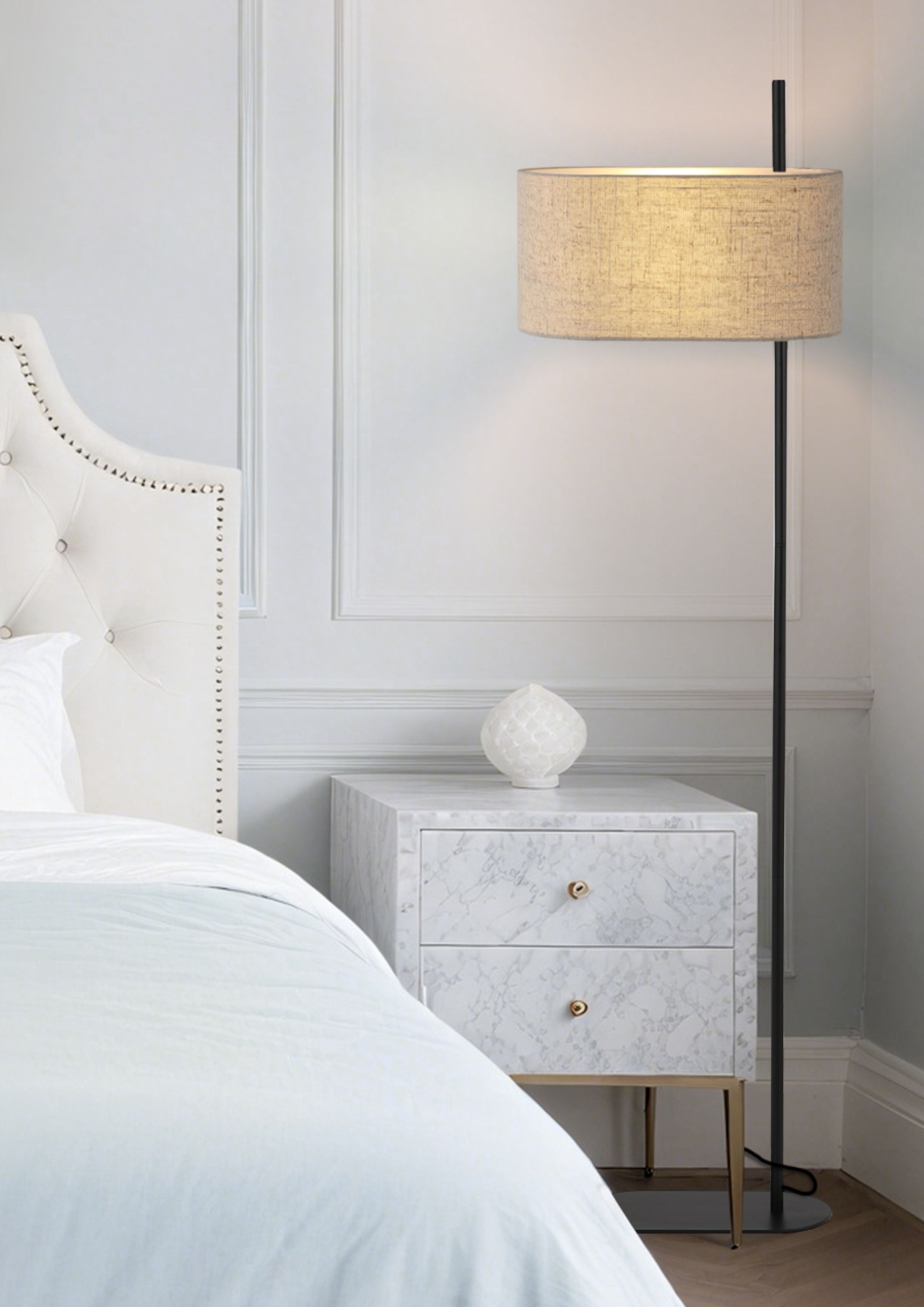 Searchlight Hessian floor lamp switched on beside a bed, standing next to a marble bedside cabinet in a styled bedroom