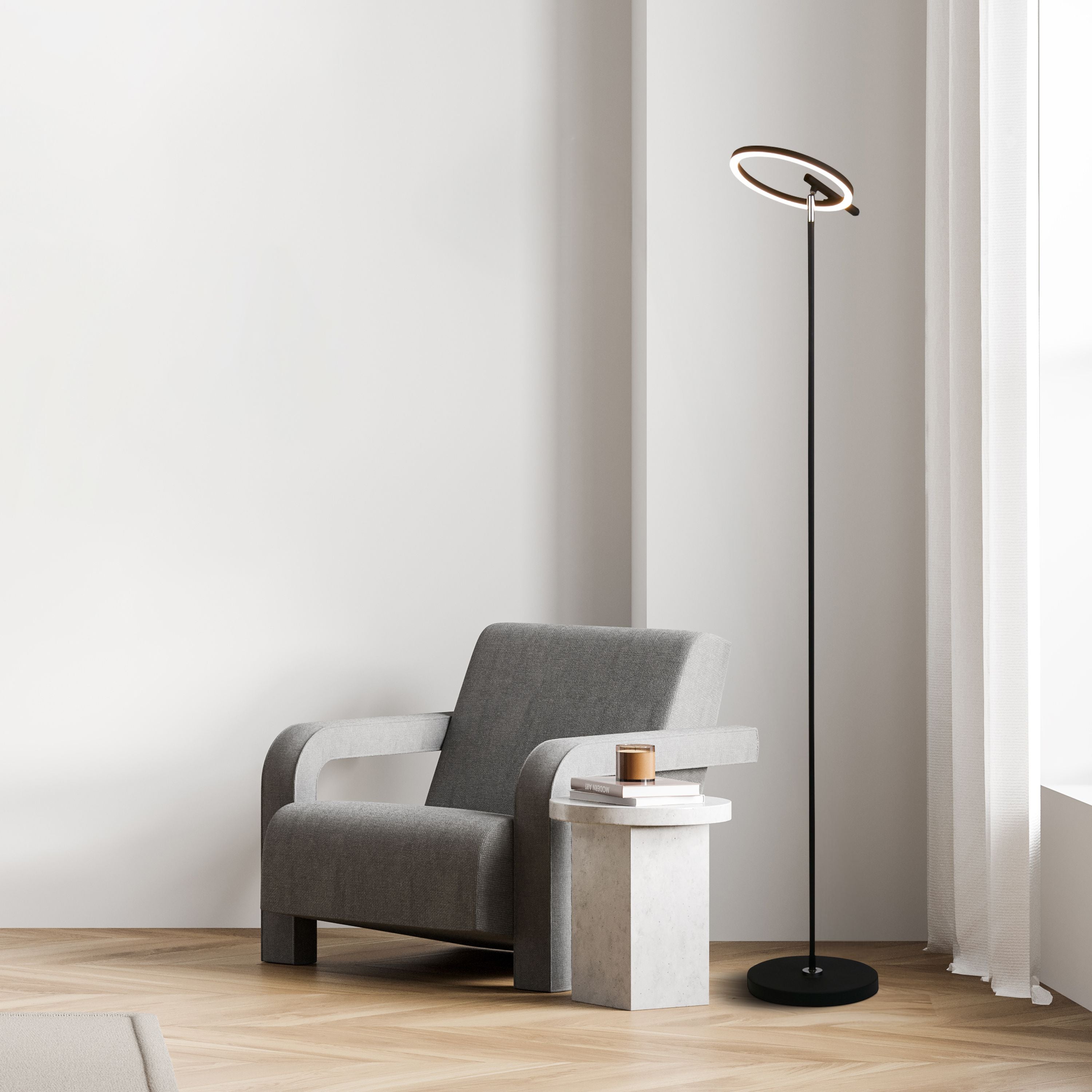 Searchlight Space LED floor lamp in black styled beside a grey armchair and a stone side table, illuminated with a warm glow