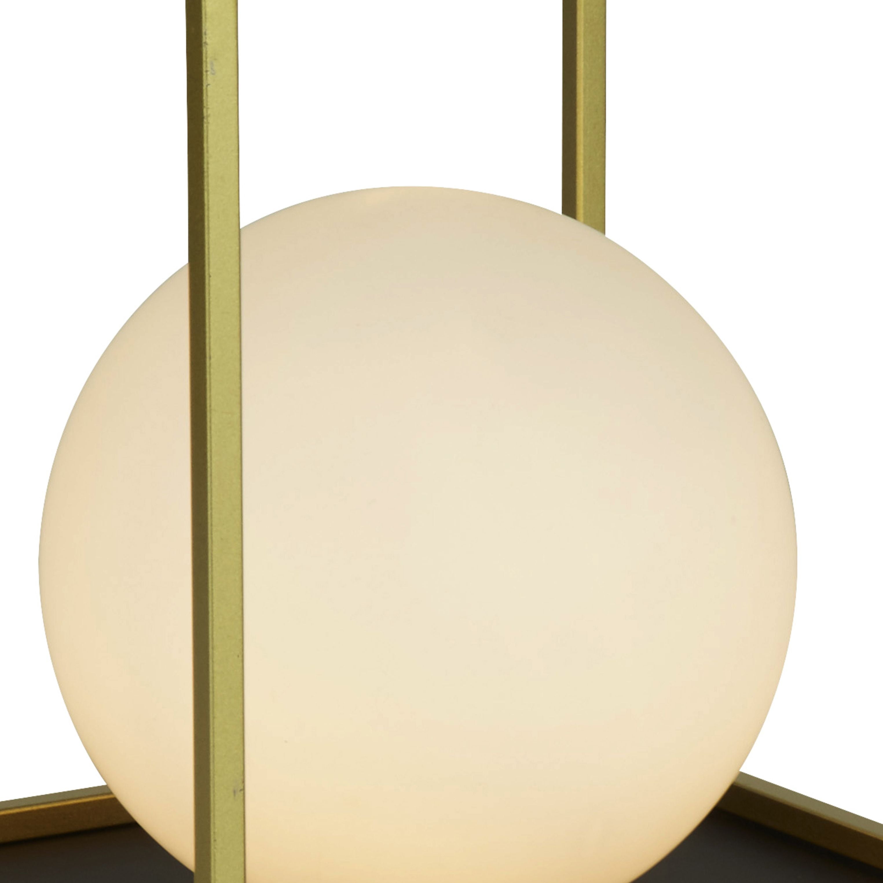 Close up of the Block table lamp's lit opal white glass globe shade within the gold metal frame