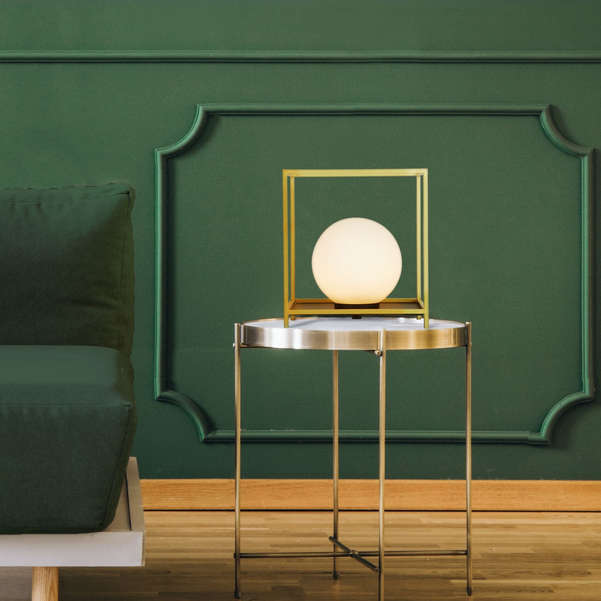 Block table lamp lit and styled on a round side table in front of a green panelled wall