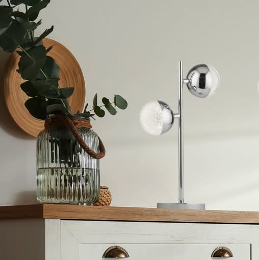 Marbles chrome table lamp styled on a wooden sideboard next to a glass vase with eucalyptus stems